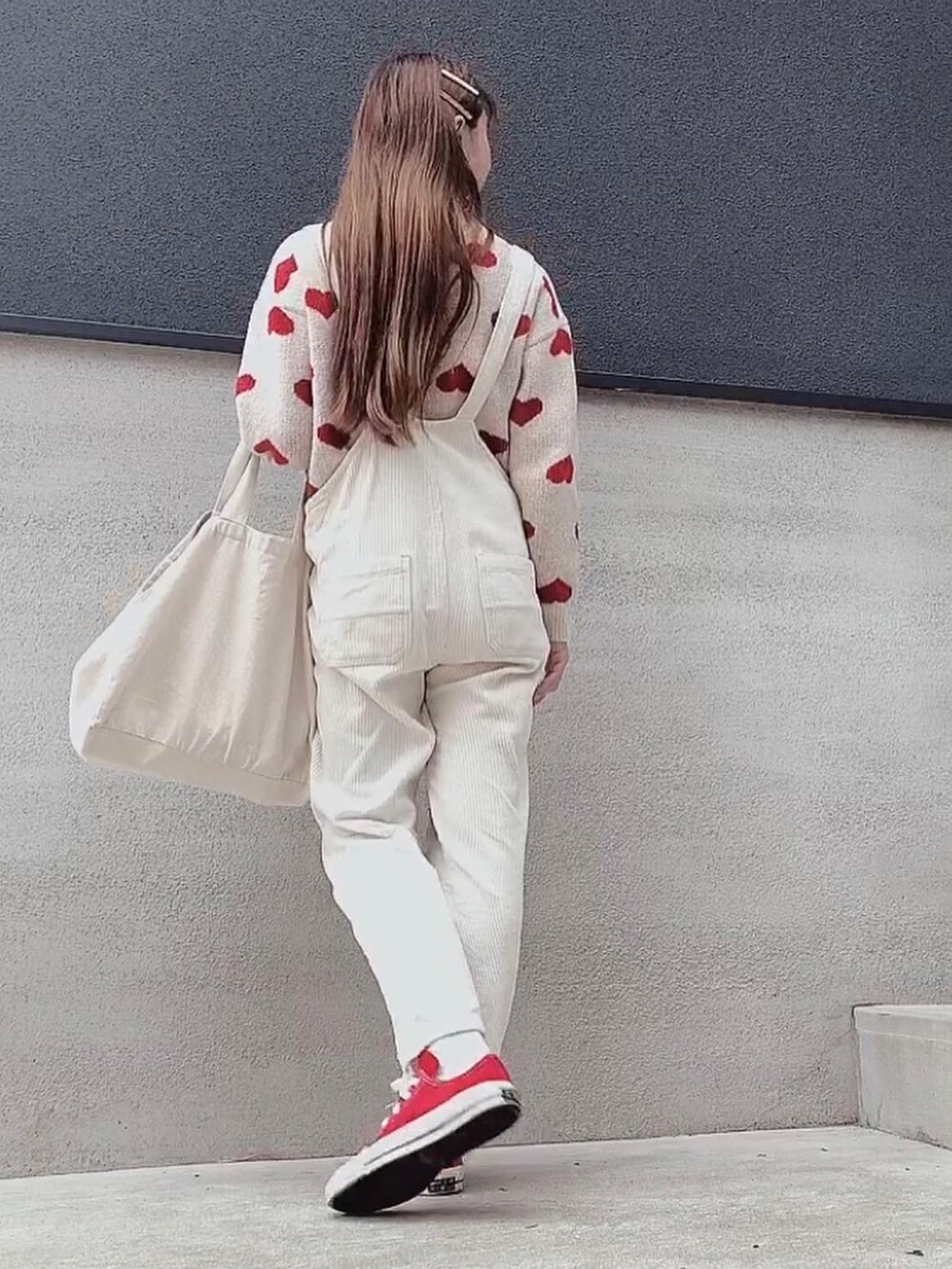 ベージュ系のサロペット/オーバーオール、レッド系のスニーカー、レッド系のニット/セーターを着用したレディースの春コーディネートの2枚目の写真