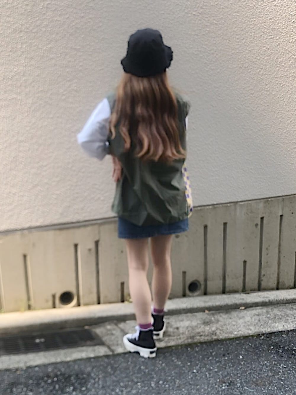 ブルー系のデニムスカート、ブラック系のスニーカー、グリーン系のベストを着用したレディースの夏コーディネートの4枚目の写真