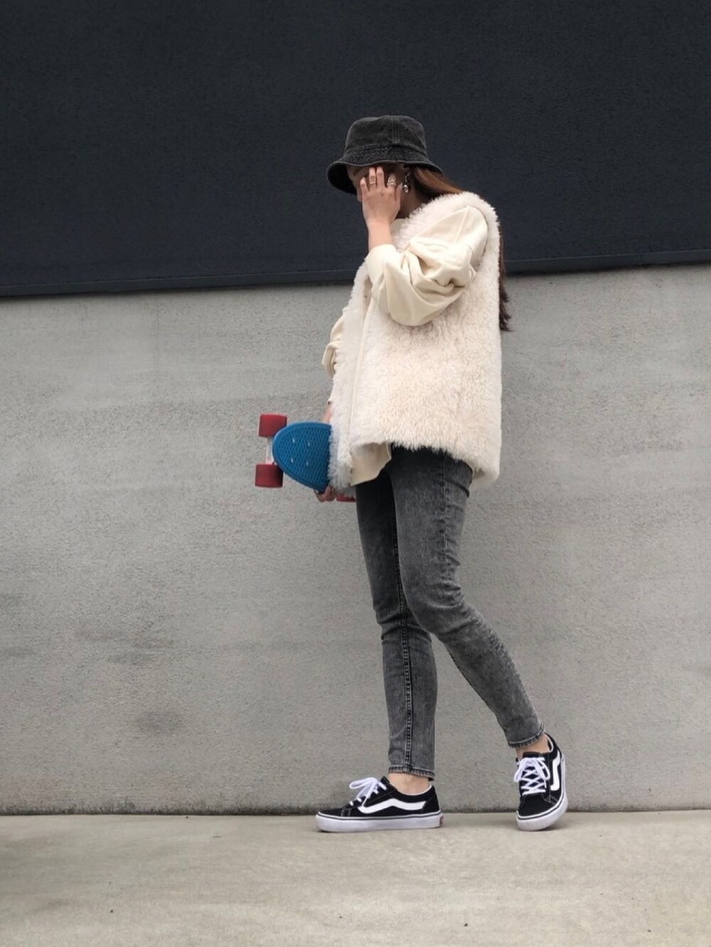 グレー系のデニムパンツ、ブラック系のスニーカー、ホワイト系のベストを着用したレディースの春コーディネートの2枚目の写真