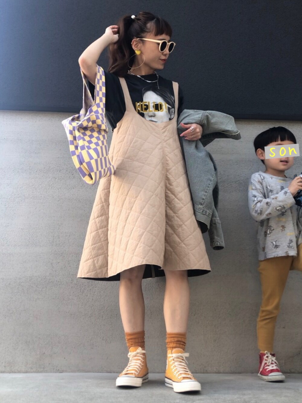 イエロー系のスニーカー、ベージュ系のジャンパースカート、ブルー系のデニムジャケットを着用したレディースの春コーディネートの2枚目の写真