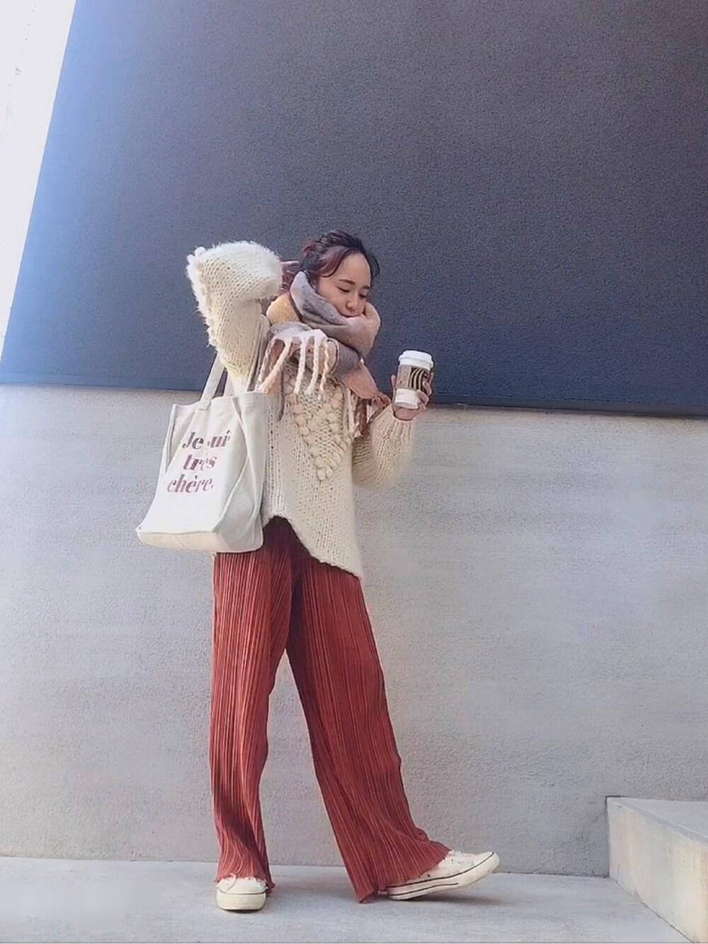 ホワイト系のトートバッグ、オレンジ系のパンツ、ホワイト系のニット/セーターを着用したレディースの冬コーディネートの3枚目の写真