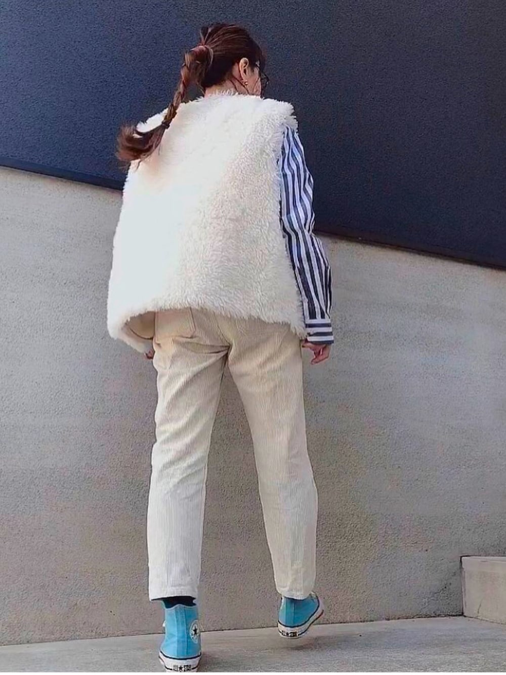 ブルー系のスニーカー、ホワイト系のベスト、ベージュ系のサロペット/オーバーオールを着用したレディースの冬コーディネートの3枚目の写真