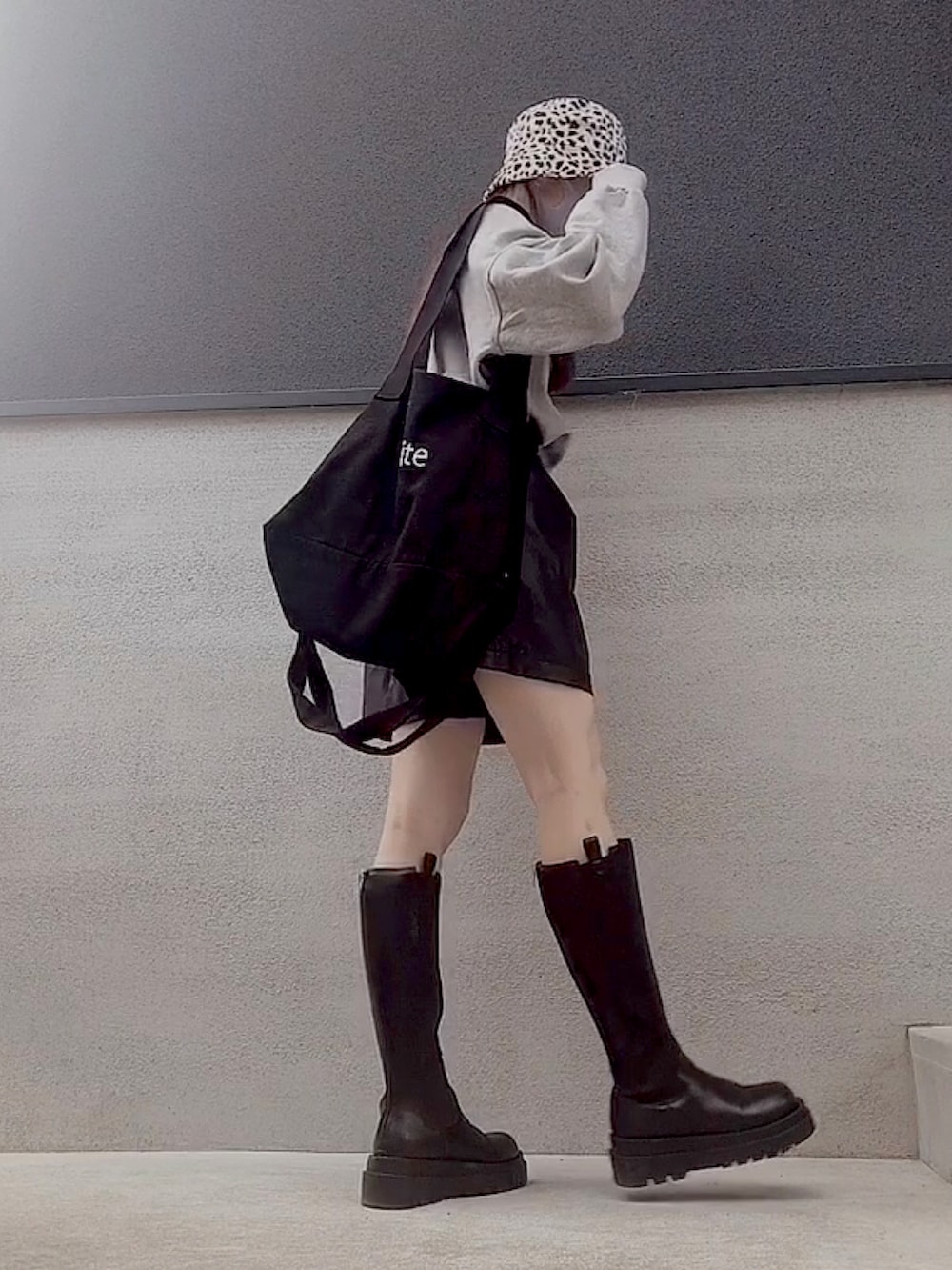 ブラック系のパンツ、グレー系のスウェット、ブラック系のトートバッグを着用したレディースの秋コーディネートの2枚目の写真