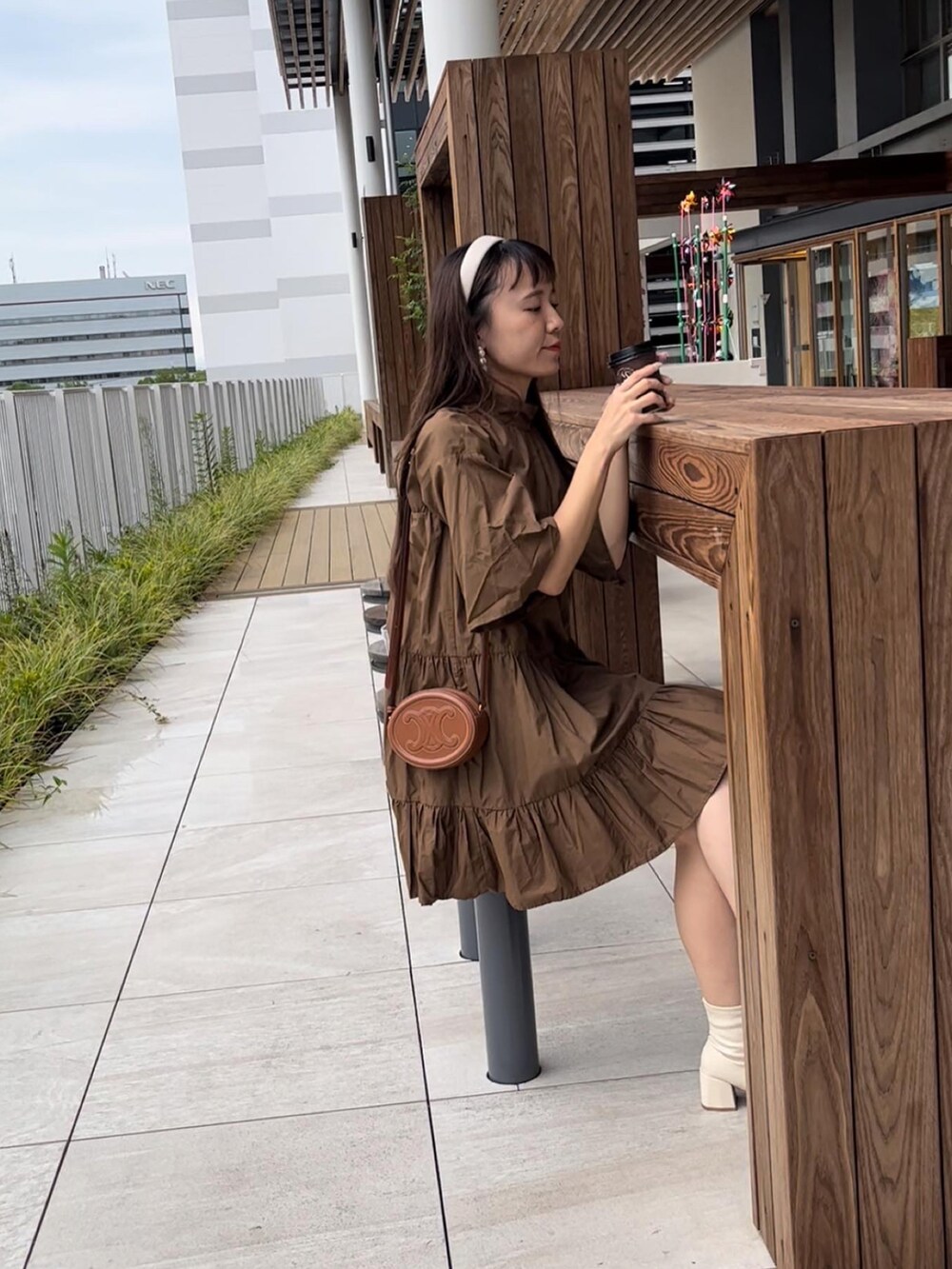 グレー系のトートバッグ、ホワイト系のブーツを着用したレディースの夏コーディネートの2枚目の写真