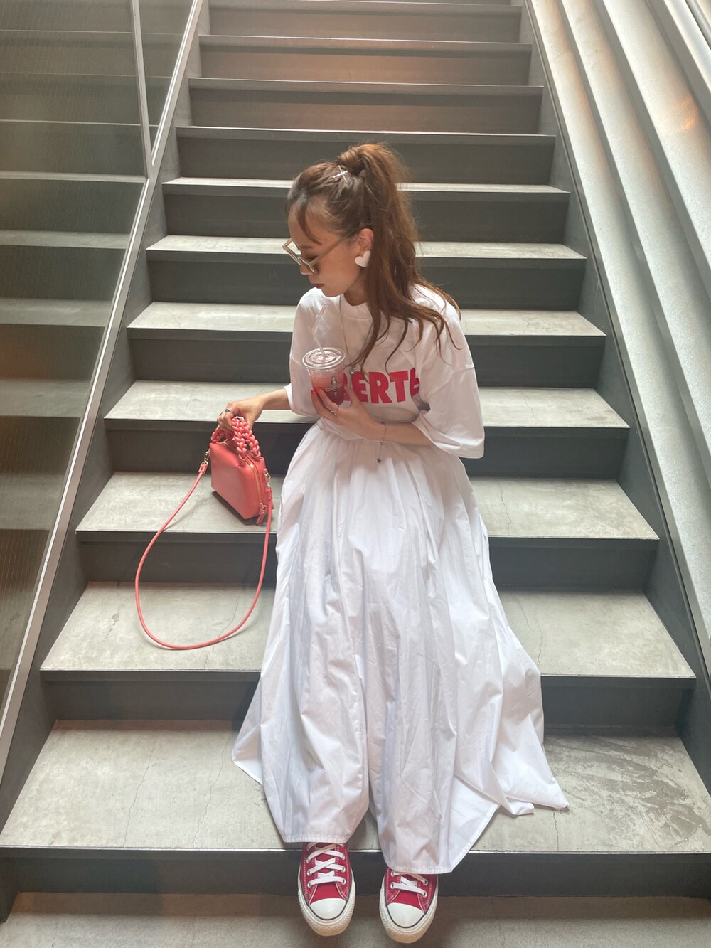 ホワイト系のスカート、ピンク系のショルダーバッグ、ホワイト系のTシャツ/カットソーを着用したレディースの春コーディネートの2枚目の写真