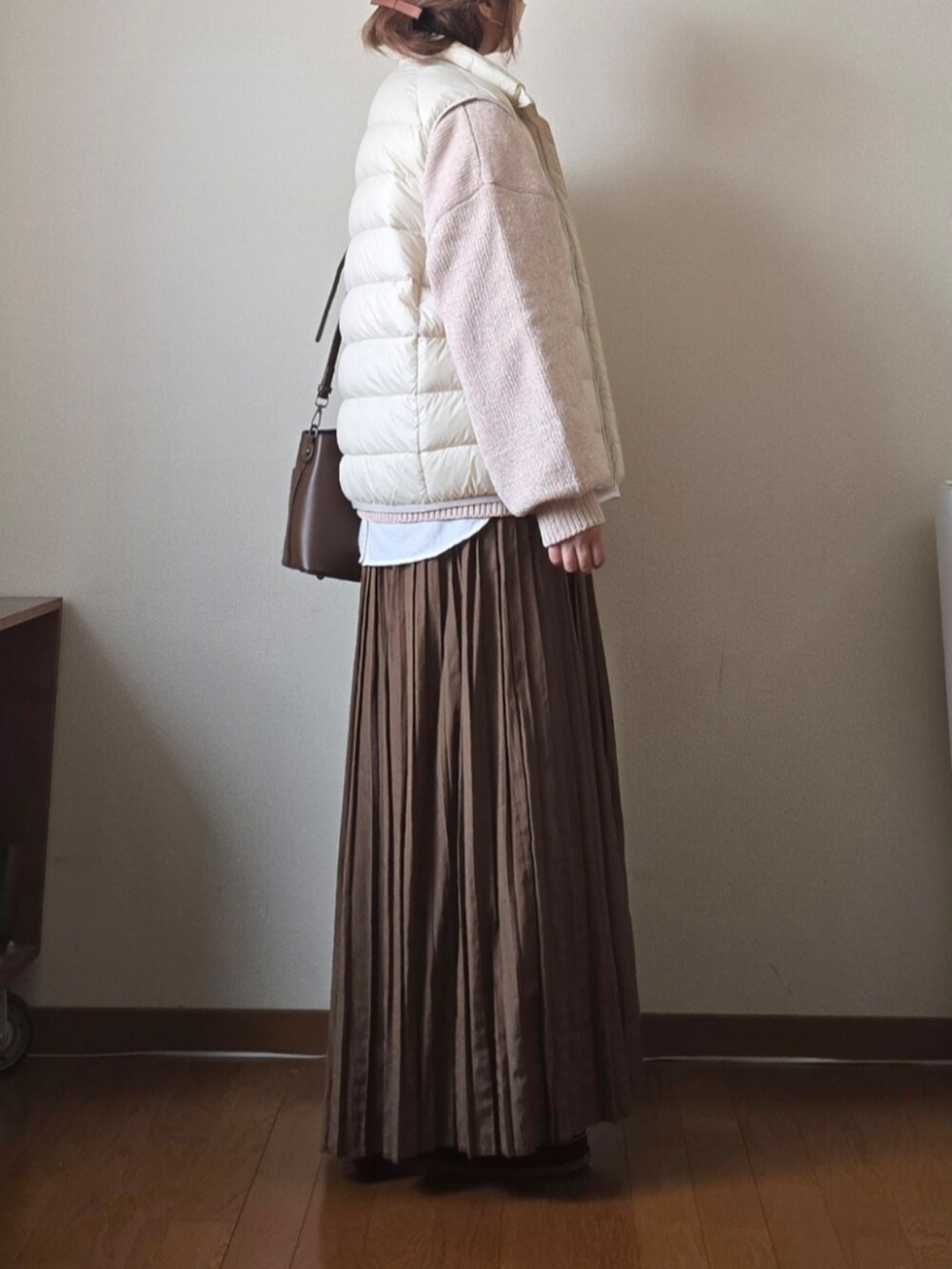 ベージュ系のニット/セーター、ホワイト系のダウンベスト、ブラウン系のハンドバッグを着用したレディースの冬コーディネートの2枚目の写真