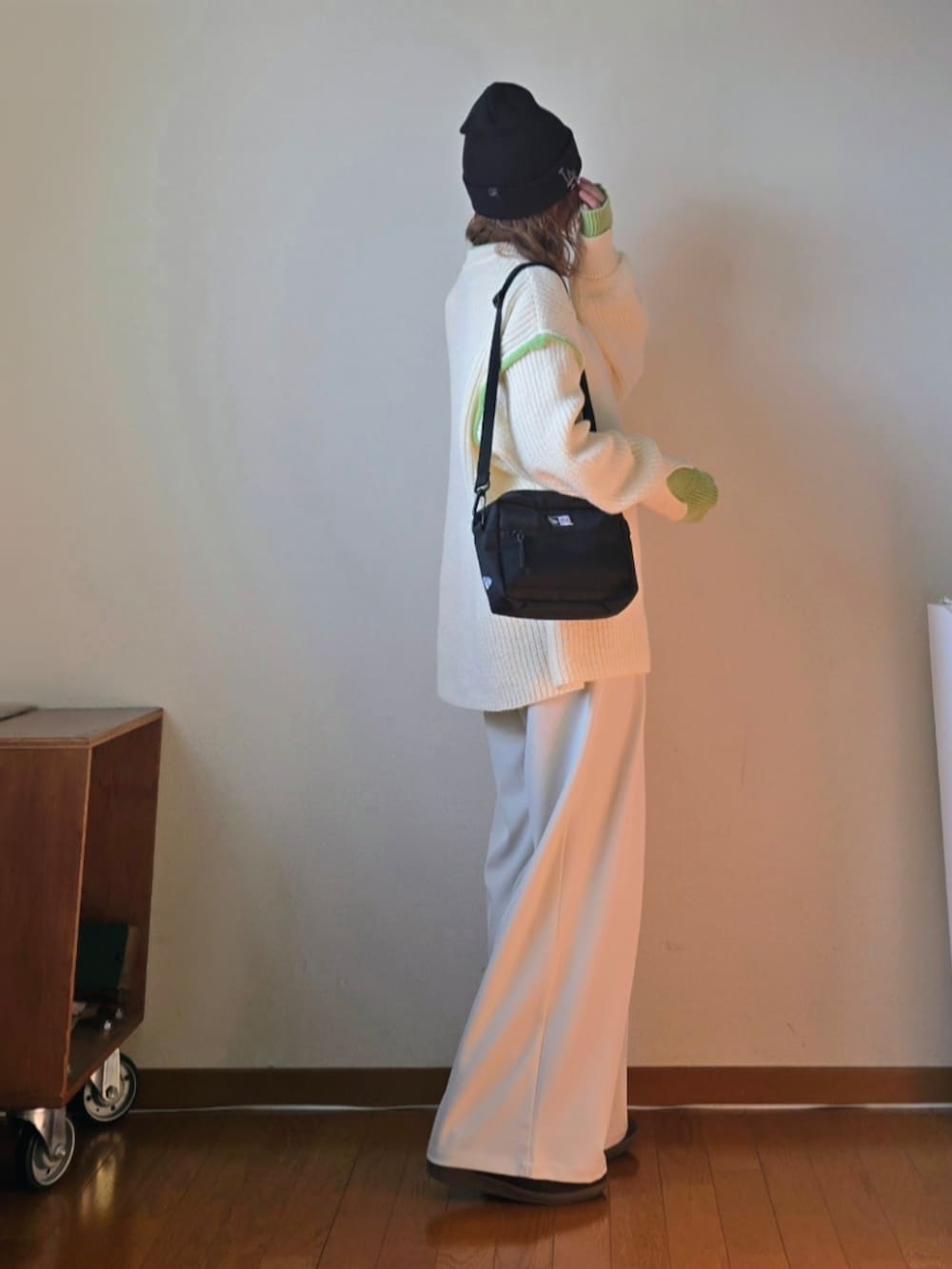 ブラック系のショルダーバッグ、ホワイト系のニット/セーター、ホワイト系のスラックスを着用したレディースの冬コーディネートの2枚目の写真