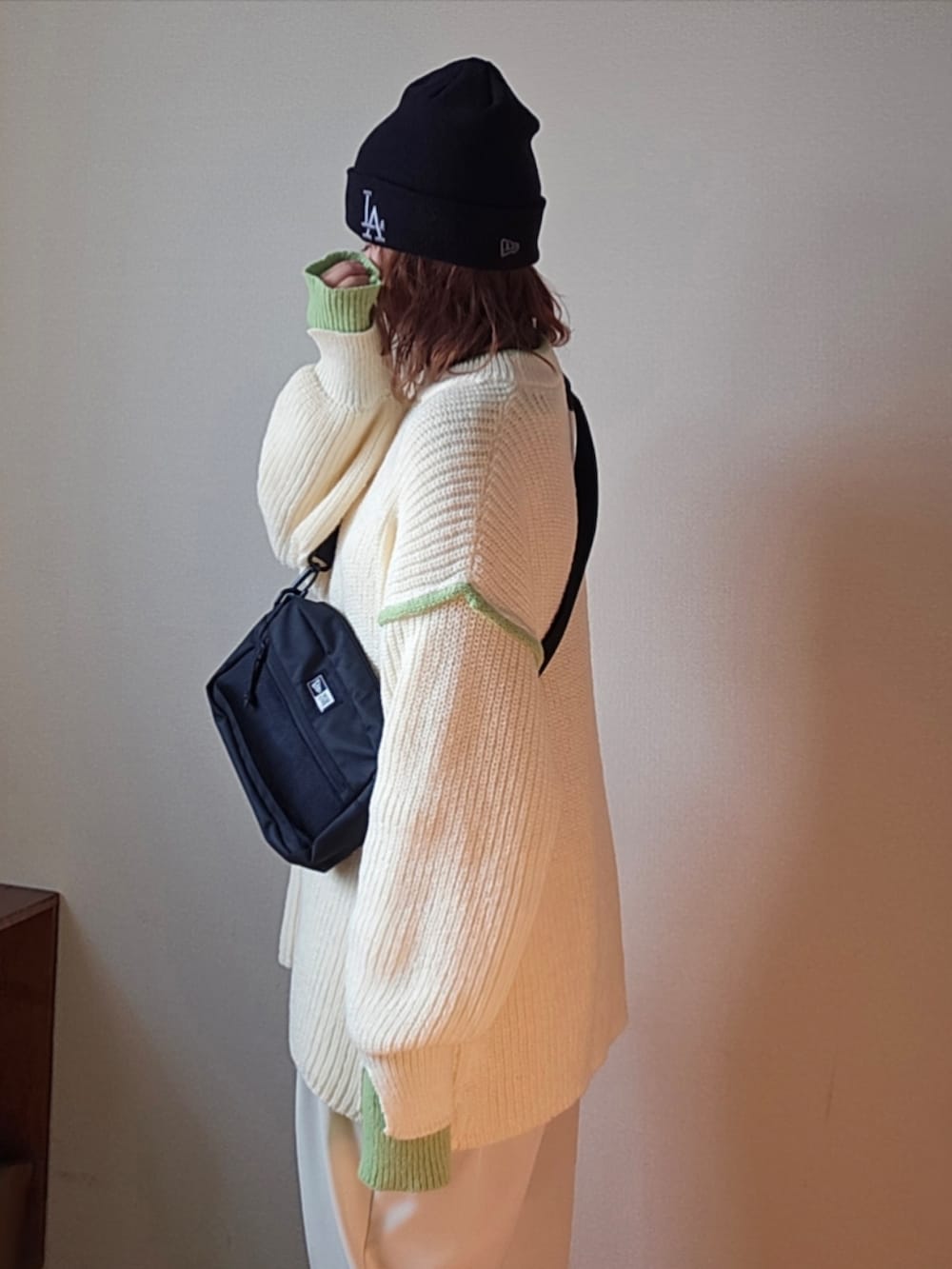 ブラック系のショルダーバッグ、ホワイト系のニット/セーター、ホワイト系のスラックスを着用したレディースの冬コーディネートの3枚目の写真