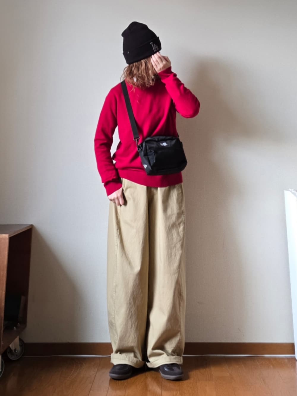 ブラック系のショルダーバッグ、レッド系のニット/セーター、ベージュ系のその他パンツを着用したレディースの冬コーディネートの2枚目の写真