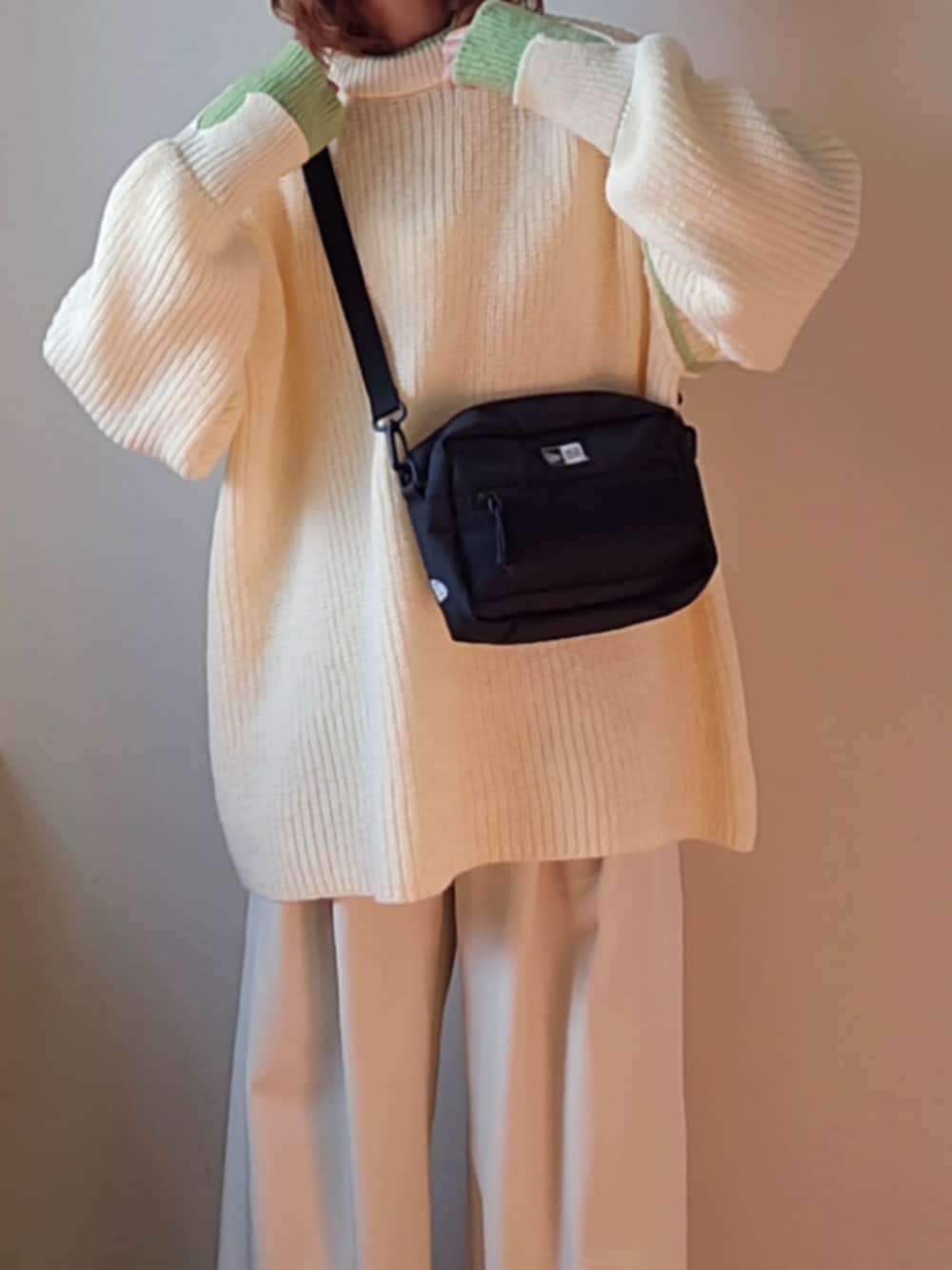 ブラック系のショルダーバッグ、ホワイト系のニット/セーター、ホワイト系のスラックスを着用したレディースの冬コーディネートの5枚目の写真