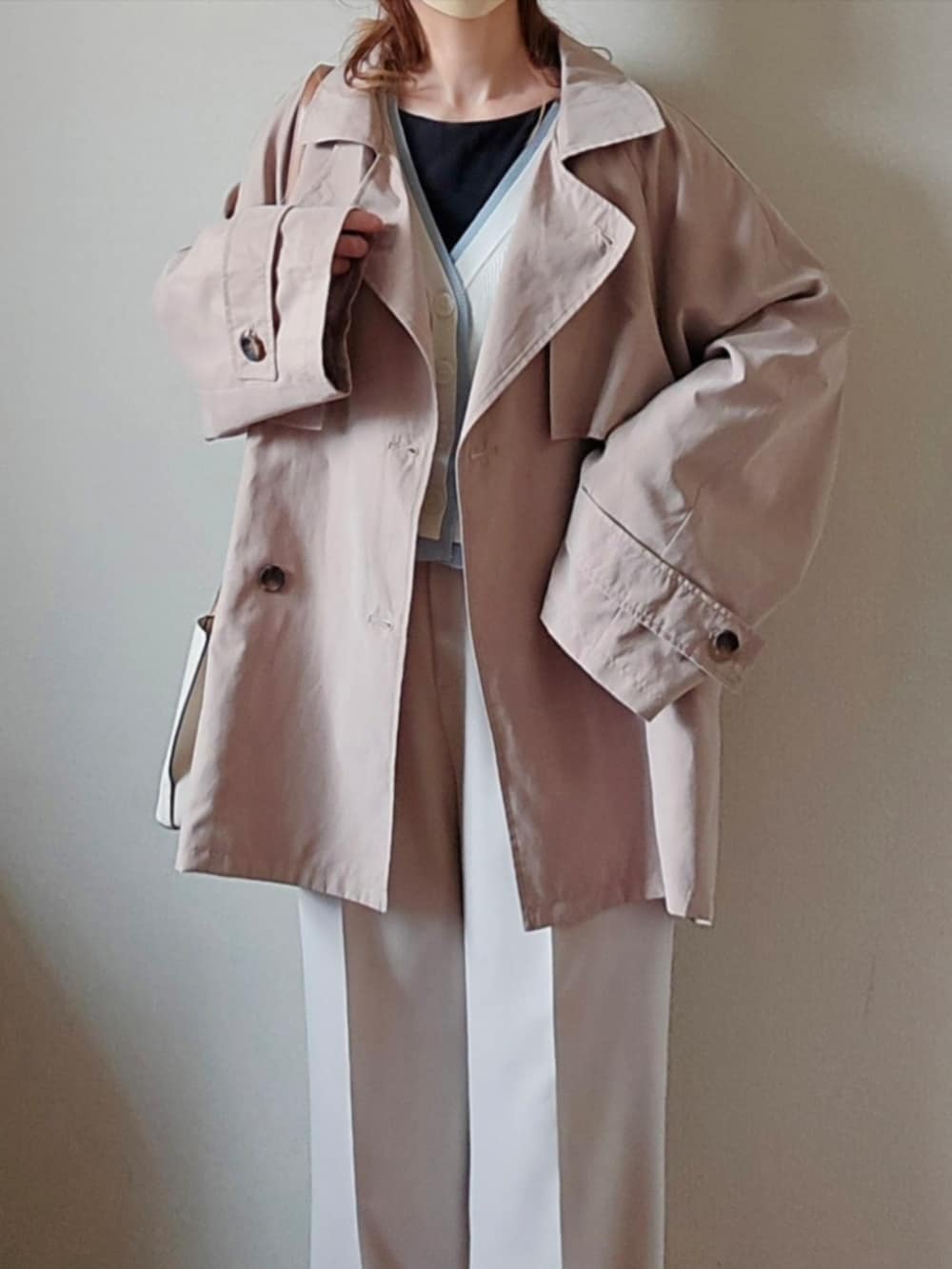 ベージュ系のトレンチコート、ホワイト系のカーディガン/ボレロ、ブラック系のパンプスを着用したレディースの春コーディネートの3枚目の写真