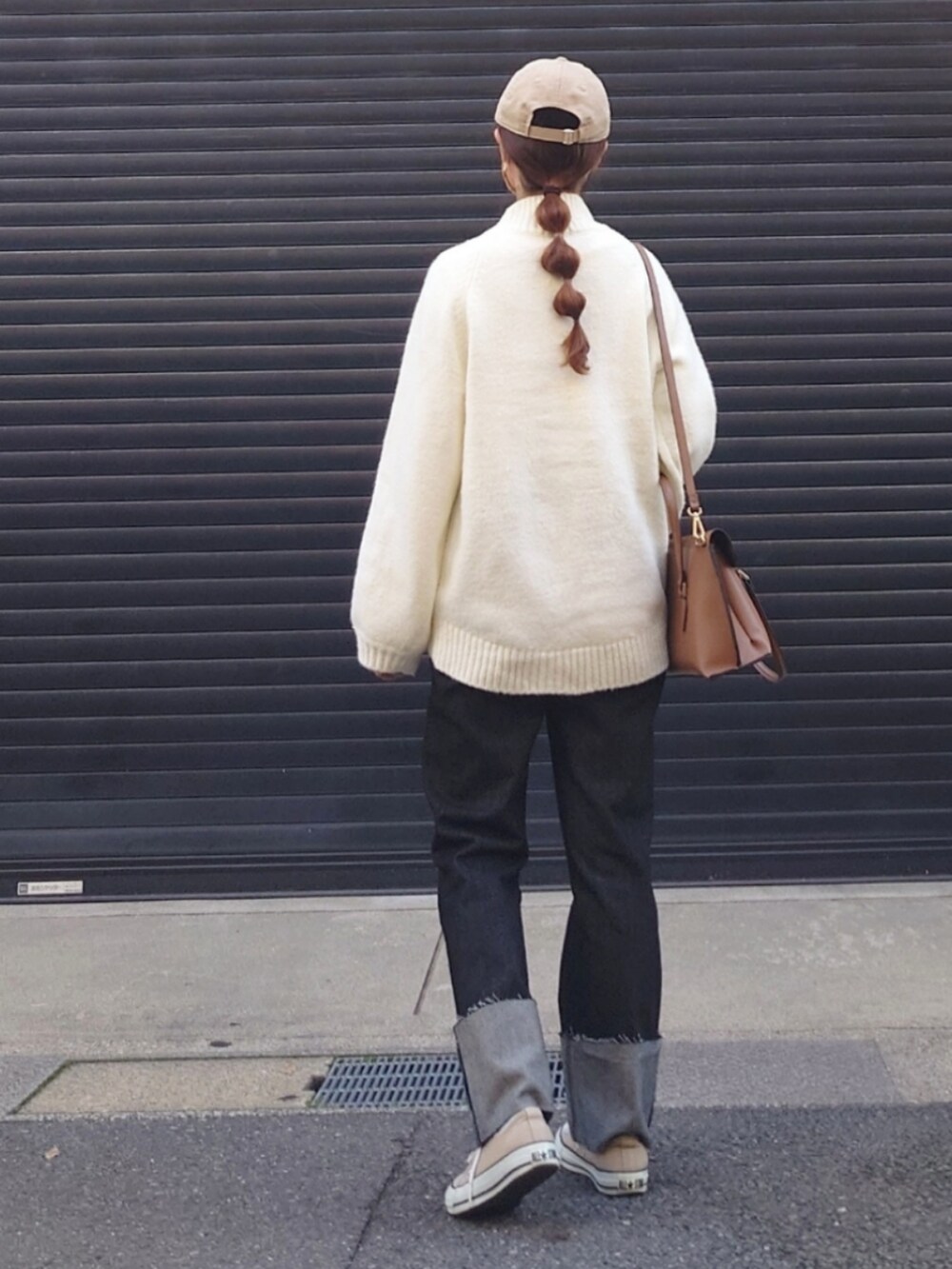 ホワイト系のニット/セーター、ブラック系のデニムパンツ、ブラウン系のハンドバッグを着用したレディースの秋コーディネートの3枚目の写真