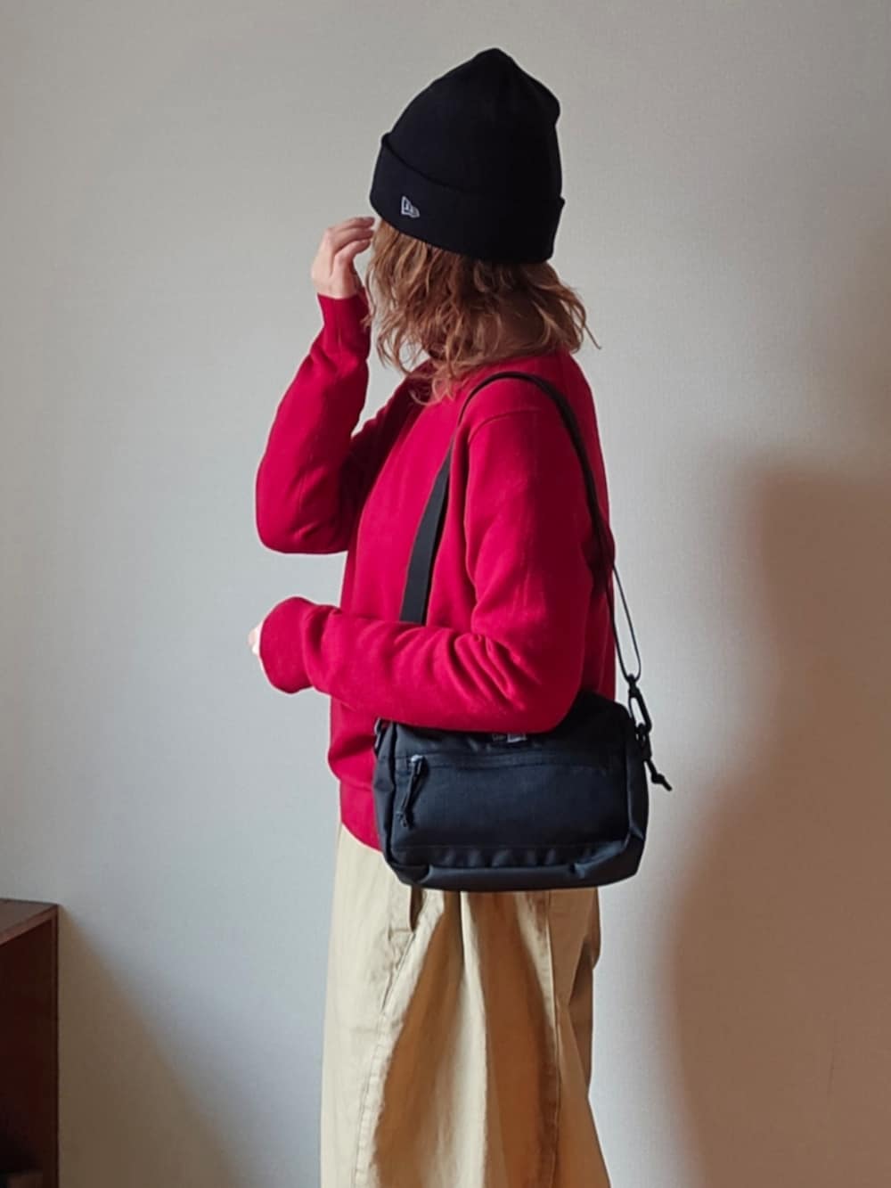 ブラック系のショルダーバッグ、レッド系のニット/セーター、ベージュ系のその他パンツを着用したレディースの冬コーディネートの4枚目の写真