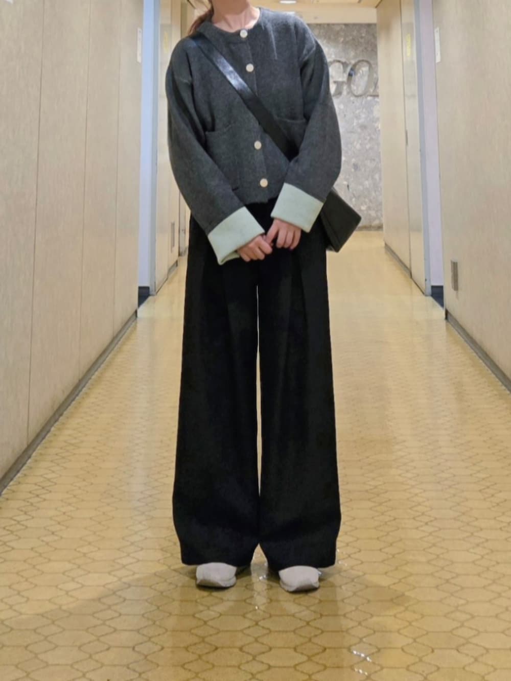 グレー系のカーディガン/ボレロ、ブラック系のスラックス、ホワイト系のブルゾンを着用したレディースの秋コーディネートの2枚目の写真