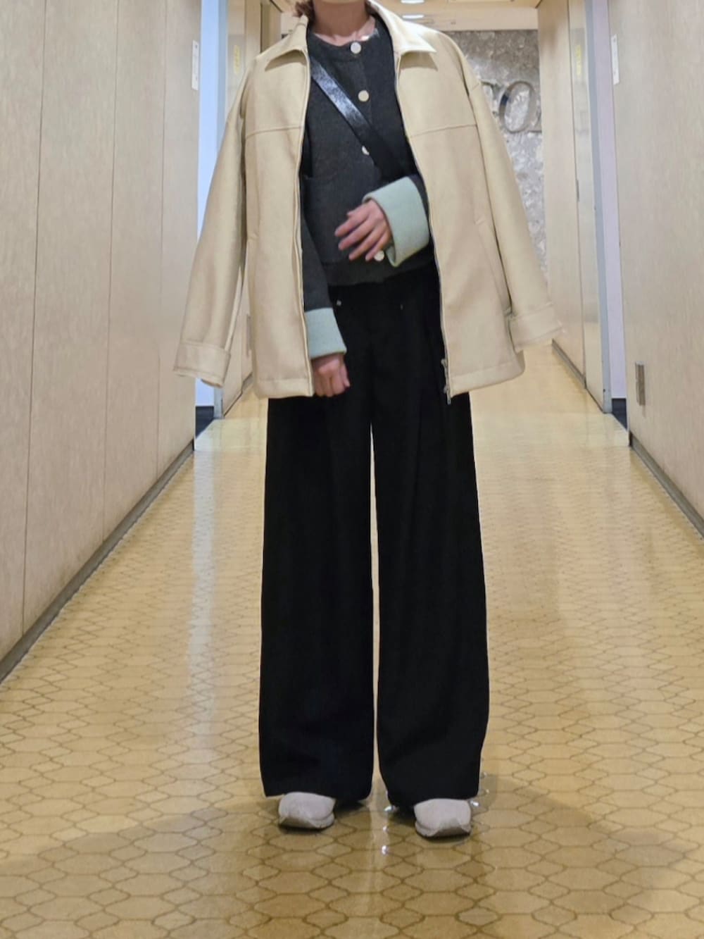 グレー系のカーディガン/ボレロ、ブラック系のスラックス、ホワイト系のブルゾンを着用したレディースの秋コーディネートの3枚目の写真