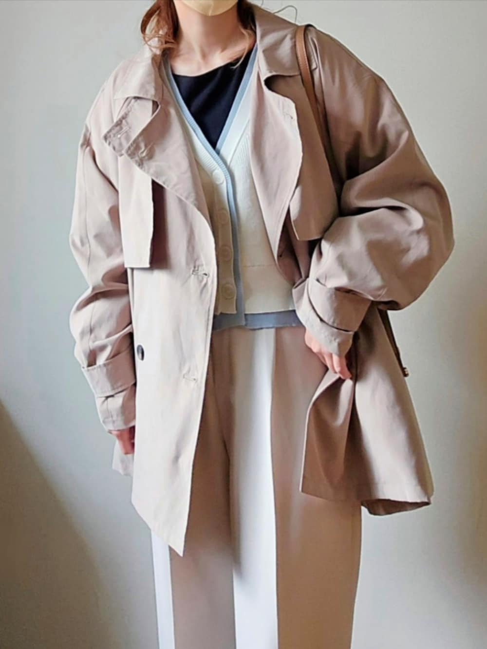 ベージュ系のトレンチコート、ホワイト系のカーディガン/ボレロ、ブラック系のパンプスを着用したレディースの春コーディネートの2枚目の写真