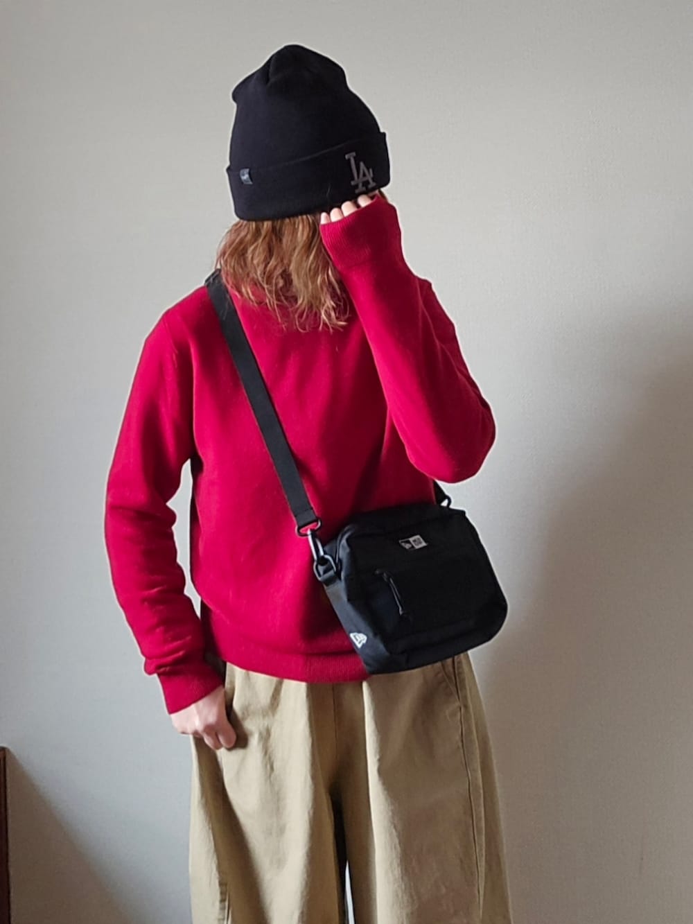 ブラック系のショルダーバッグ、レッド系のニット/セーター、ベージュ系のその他パンツを着用したレディースの冬コーディネートの5枚目の写真