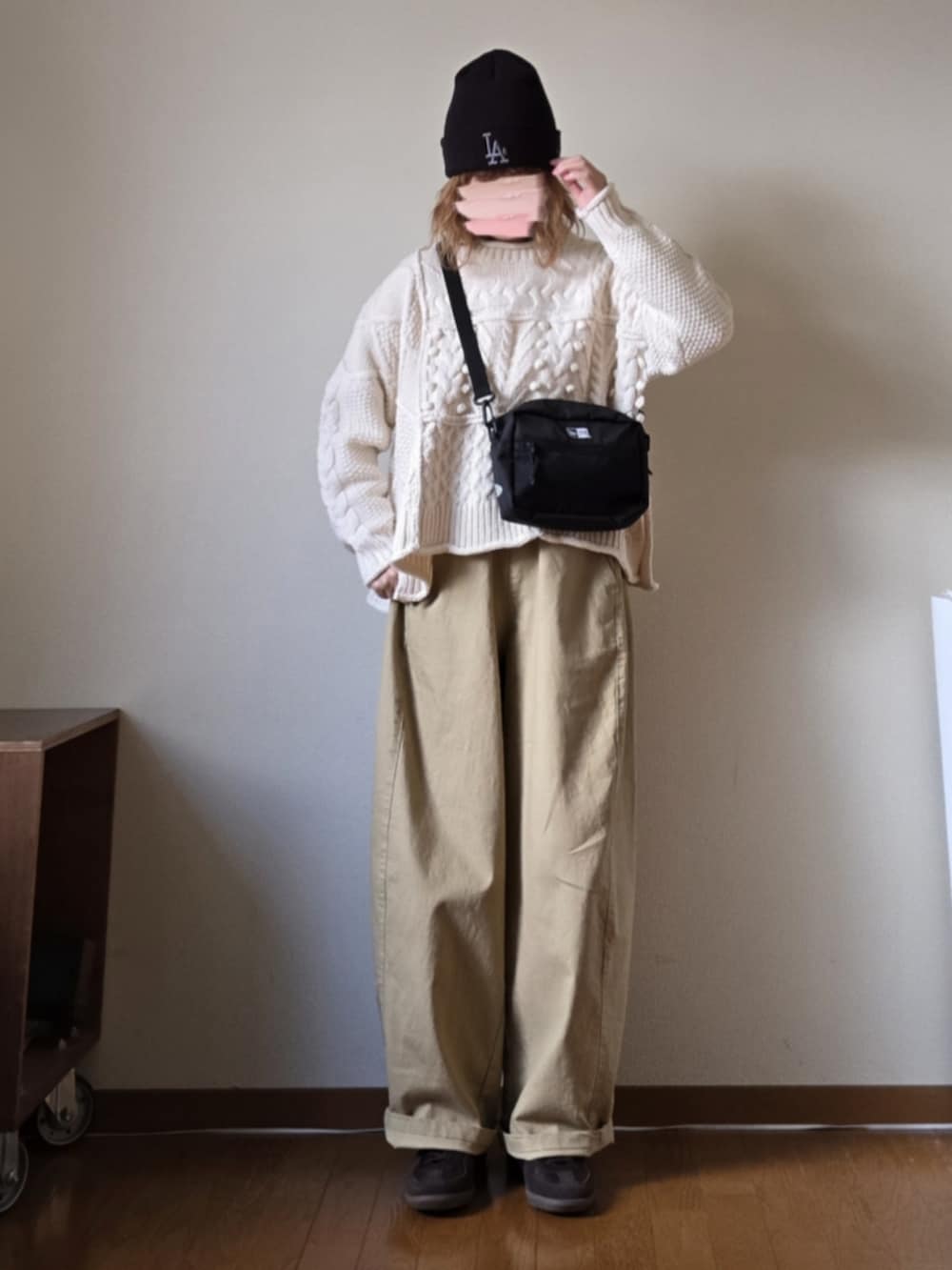 ブラック系のショルダーバッグ、ベージュ系のその他パンツ、ホワイト系のニット/セーターを着用したレディースの冬コーディネートの2枚目の写真
