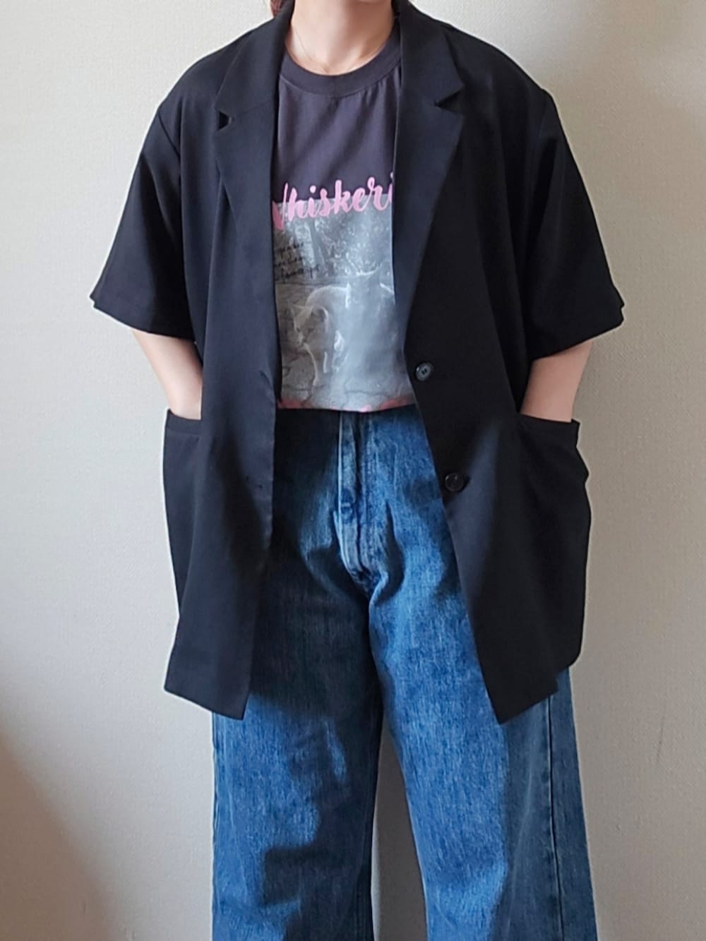 グレー系のTシャツ/カットソー、ブラック系のテーラードジャケット、ブルー系のデニムパンツを着用したレディースの夏コーディネートの4枚目の写真