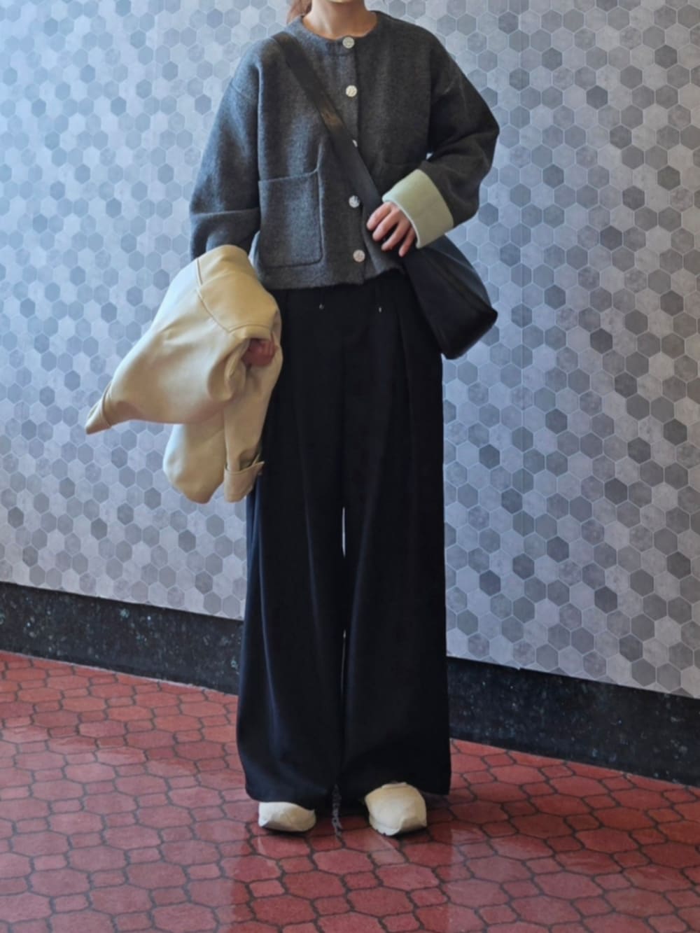 グレー系のカーディガン/ボレロ、ブラック系のスラックス、ホワイト系のブルゾンを着用したレディースの秋コーディネートの4枚目の写真