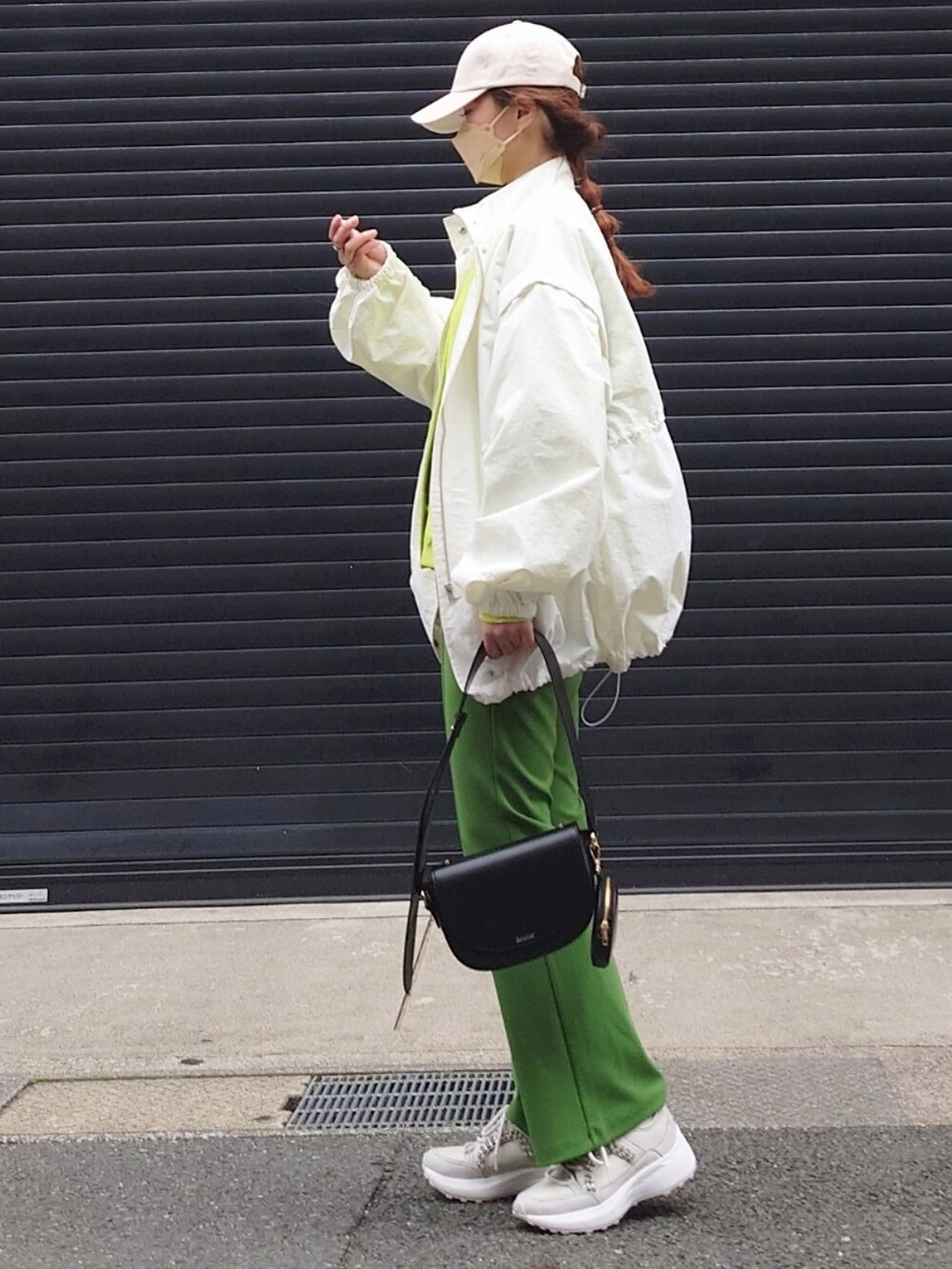 ホワイト系のブルゾン、グリーン系のカーディガン/ボレロ、グリーン系のパンツを着用したレディースの春コーディネートの2枚目の写真