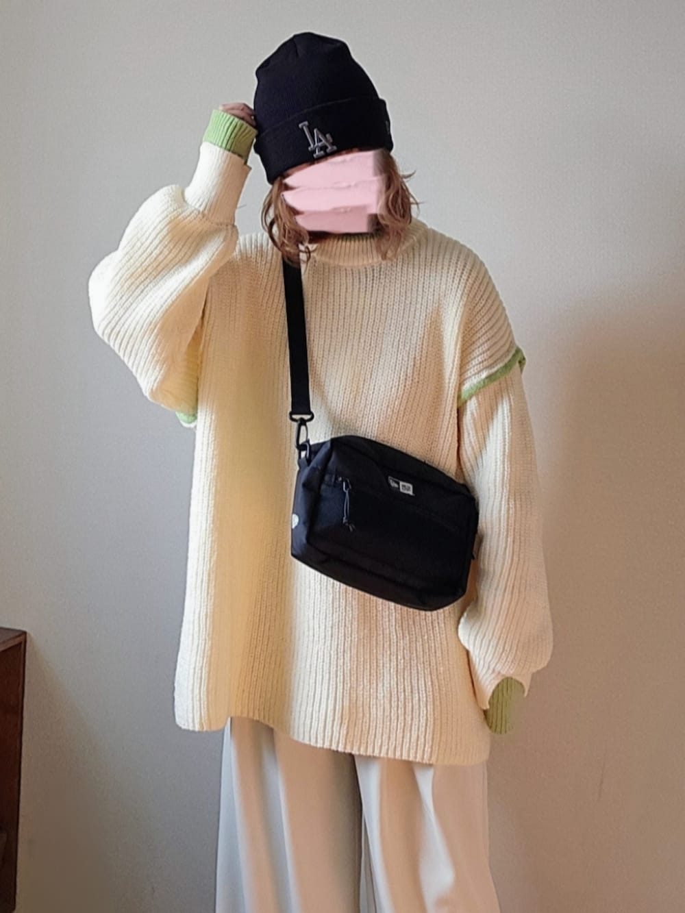 ブラック系のショルダーバッグ、ホワイト系のニット/セーター、ホワイト系のスラックスを着用したレディースの冬コーディネートの4枚目の写真