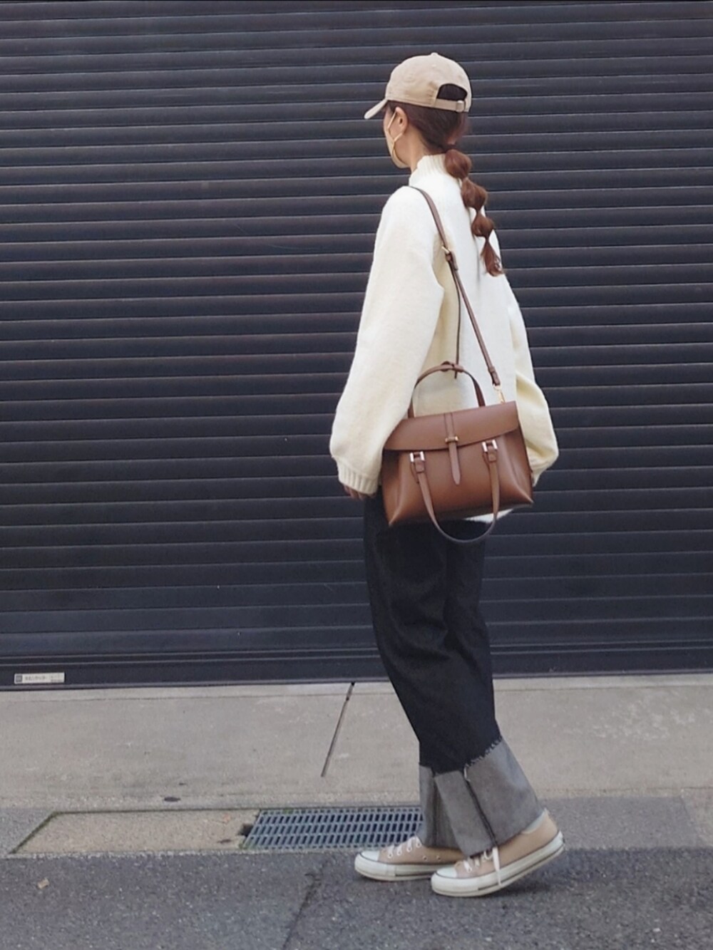 ホワイト系のニット/セーター、ブラック系のデニムパンツ、ブラウン系のハンドバッグを着用したレディースの秋コーディネートの2枚目の写真