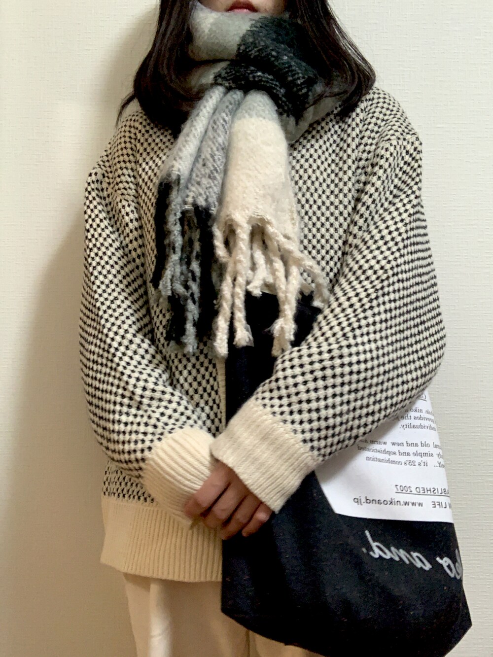 ブラック系のトートバッグ、ホワイト系のニット/セーター、ホワイト系のパンツを着用したレディースの秋コーディネートの2枚目の写真