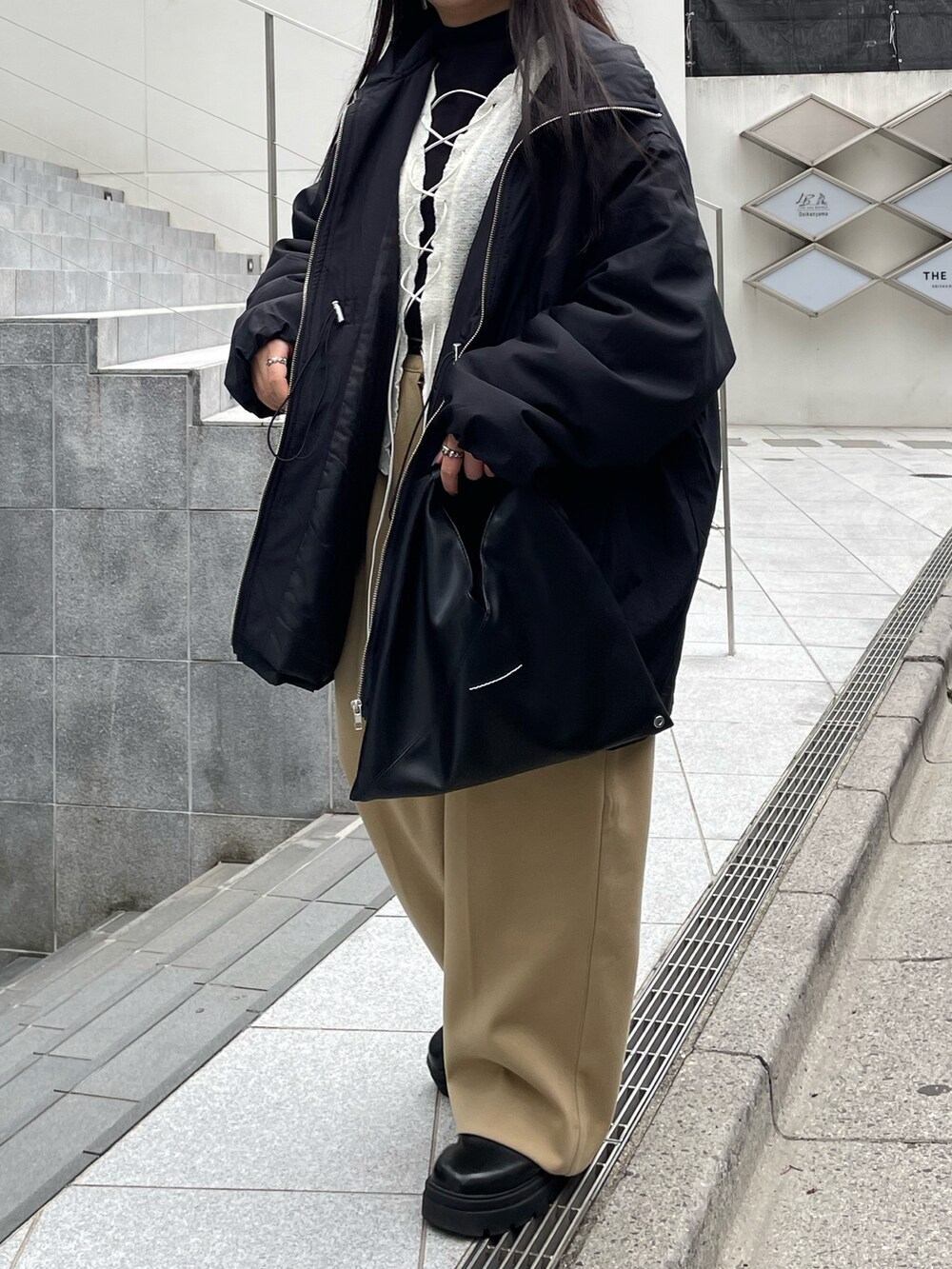 ブラック系のブーツ、ブラック系のハンドバッグ、ベージュ系のパンツを着用したレディースの冬コーディネートの2枚目の写真