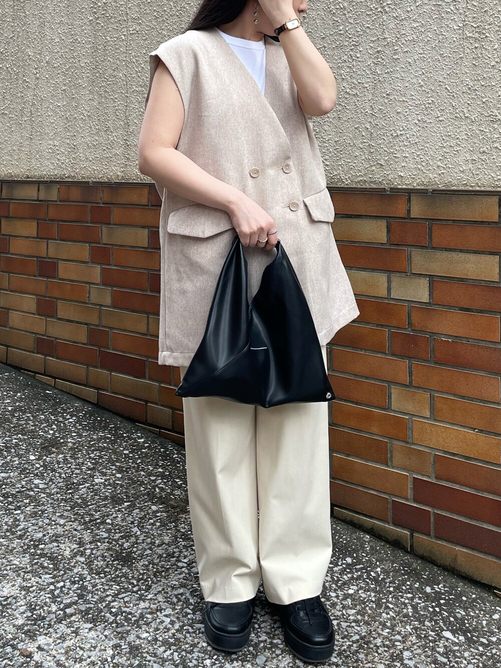 ホワイト系のタンクトップ、ベージュ系のベスト、ベージュ系のパンツを着用したレディースの秋コーディネートの3枚目の写真