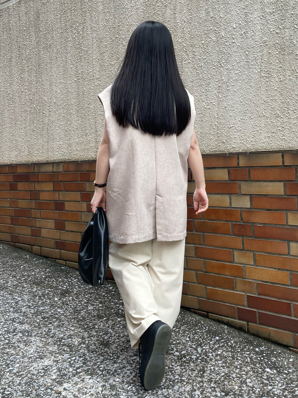 ホワイト系のタンクトップ、ベージュ系のベスト、ベージュ系のパンツを着用したレディースの秋コーディネートの4枚目の写真