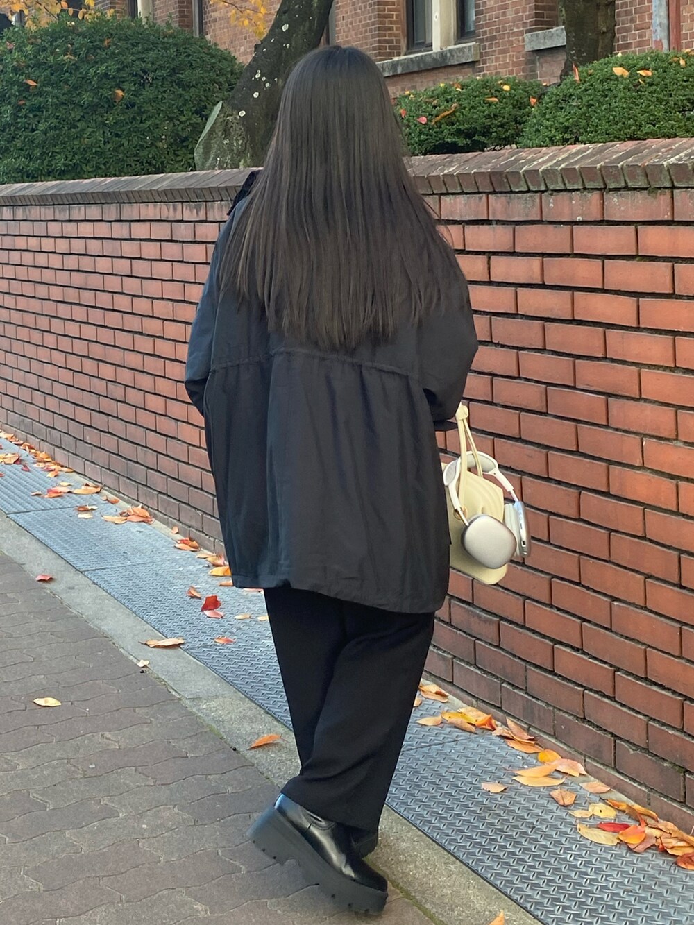 ベージュ系のショルダーバッグ、ブラック系のブルゾン、ホワイト系のニット/セーターを着用したレディースの冬コーディネートの2枚目の写真