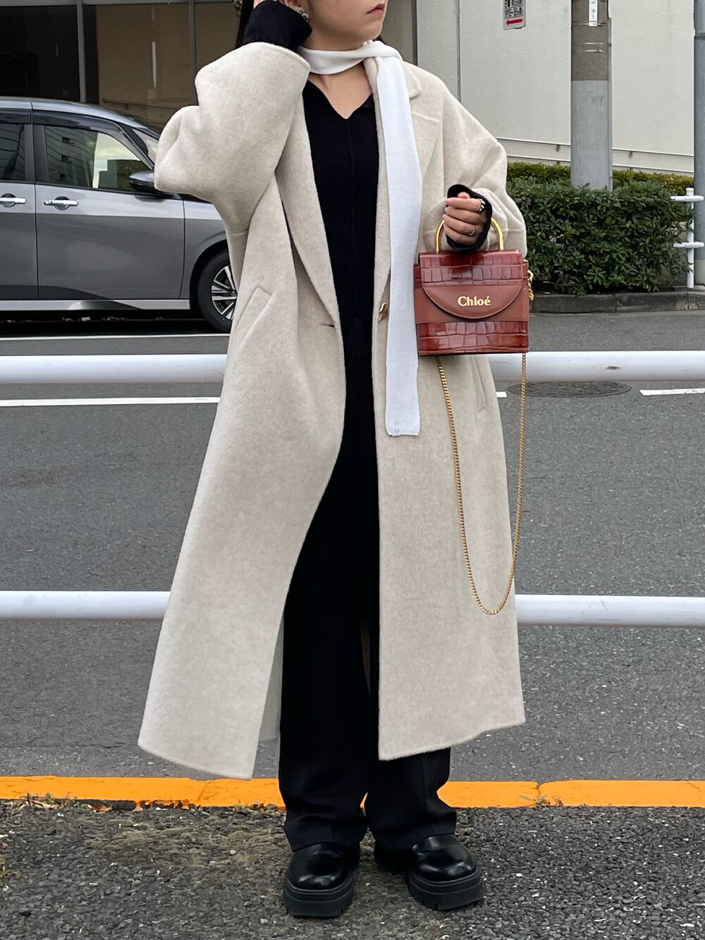 ブラック系のブーツ、ホワイト系のジャケット/アウター、ホワイト系のストール/ショールを着用したレディースの冬コーディネートの2枚目の写真