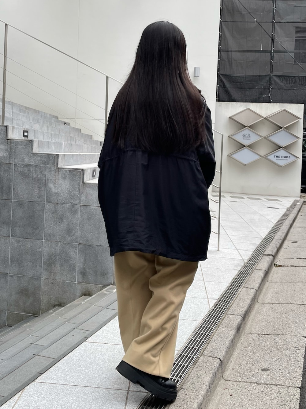 ブラック系のブーツ、ブラック系のハンドバッグ、ベージュ系のパンツを着用したレディースの冬コーディネートの3枚目の写真