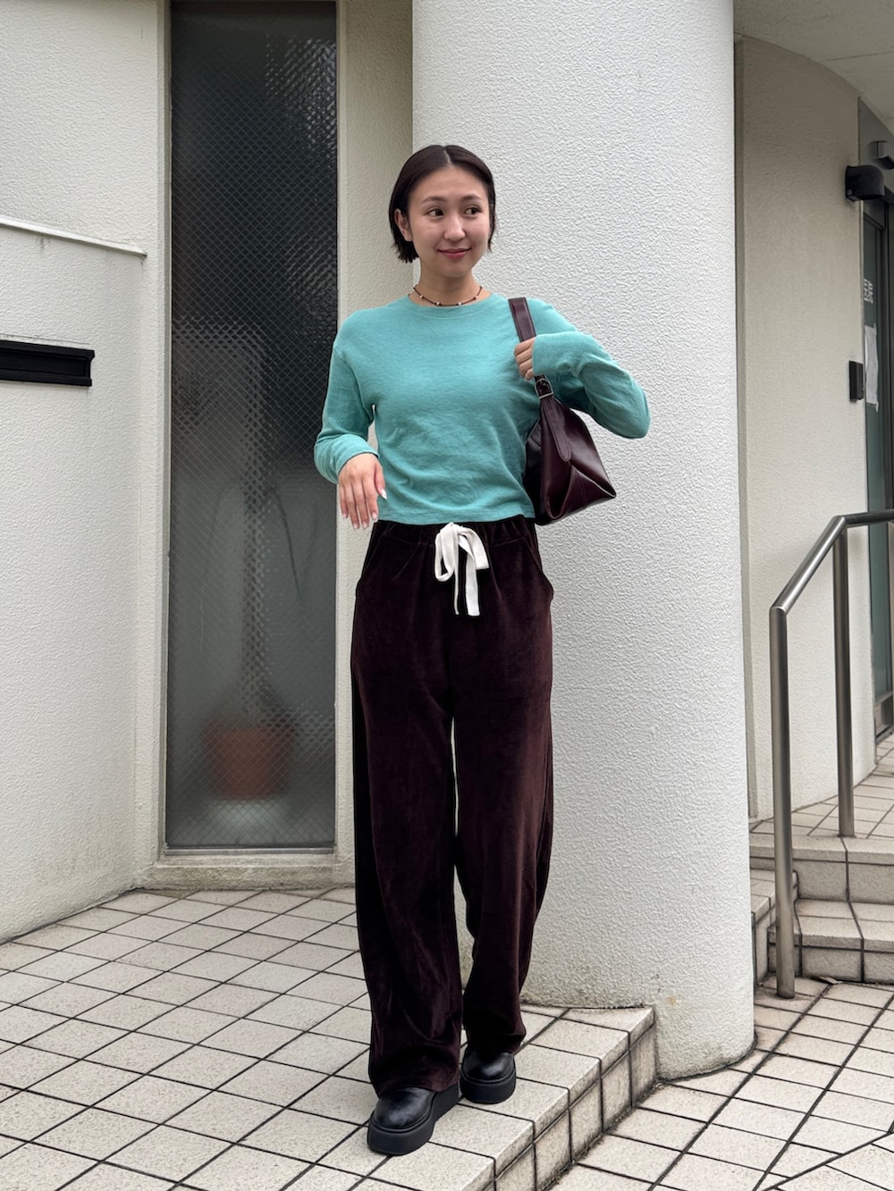 グリーン系のTシャツ/カットソー、ブラウン系のスウェットパンツ、ブラック系のブーツを着用したレディースの秋コーディネートの2枚目の写真