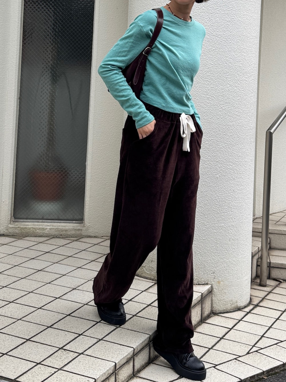 グリーン系のTシャツ/カットソー、ブラウン系のスウェットパンツ、ブラック系のブーツを着用したレディースの秋コーディネートの3枚目の写真