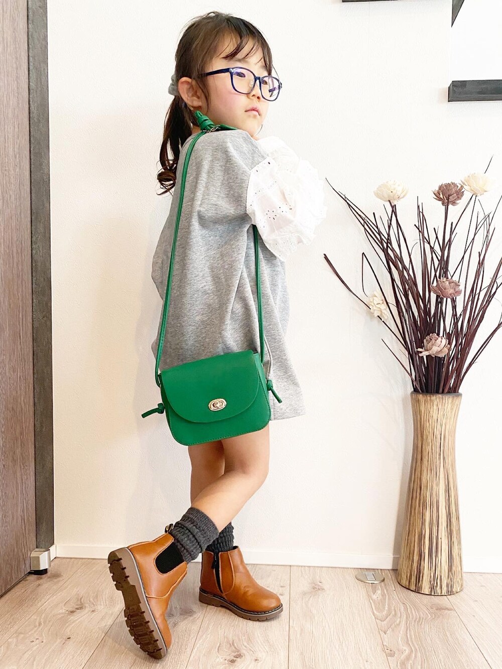 グリーン系のショルダーバッグ、ブラウン系のブーツ、グレー系のワンピース/ドレスを着用したキッズの冬コーディネートの2枚目の写真