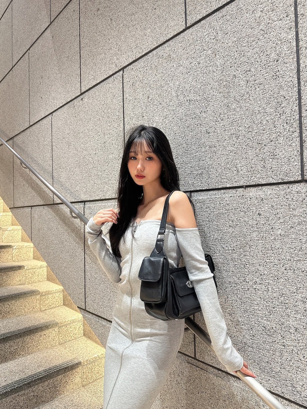 グレー系のワンピース、ブラック系のハンドバッグを着用したレディースの秋コーディネートの2枚目の写真