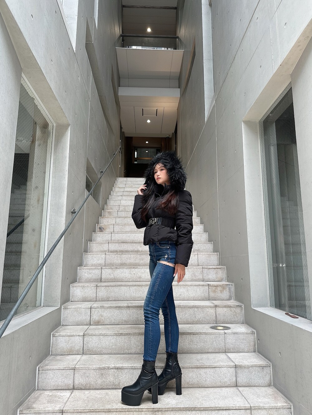 ブラック系のダウンジャケット/コート、ブラック系のブーツ、ブルー系のデニムパンツを着用したレディースの秋コーディネートの3枚目の写真