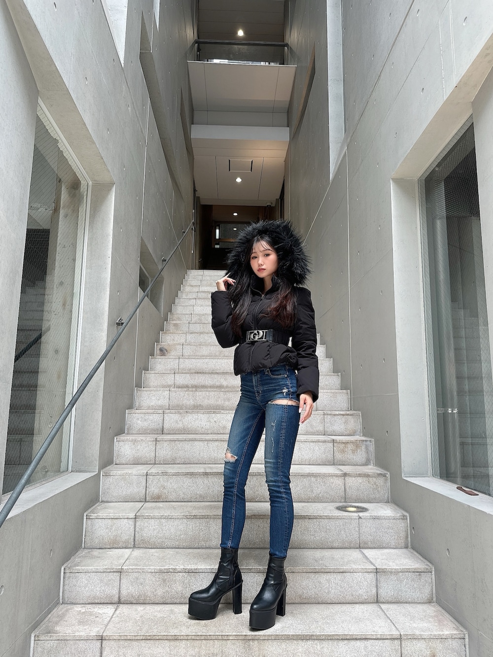 ブラック系のダウンジャケット/コート、ブラック系のブーツ、ブルー系のデニムパンツを着用したレディースの秋コーディネートの2枚目の写真