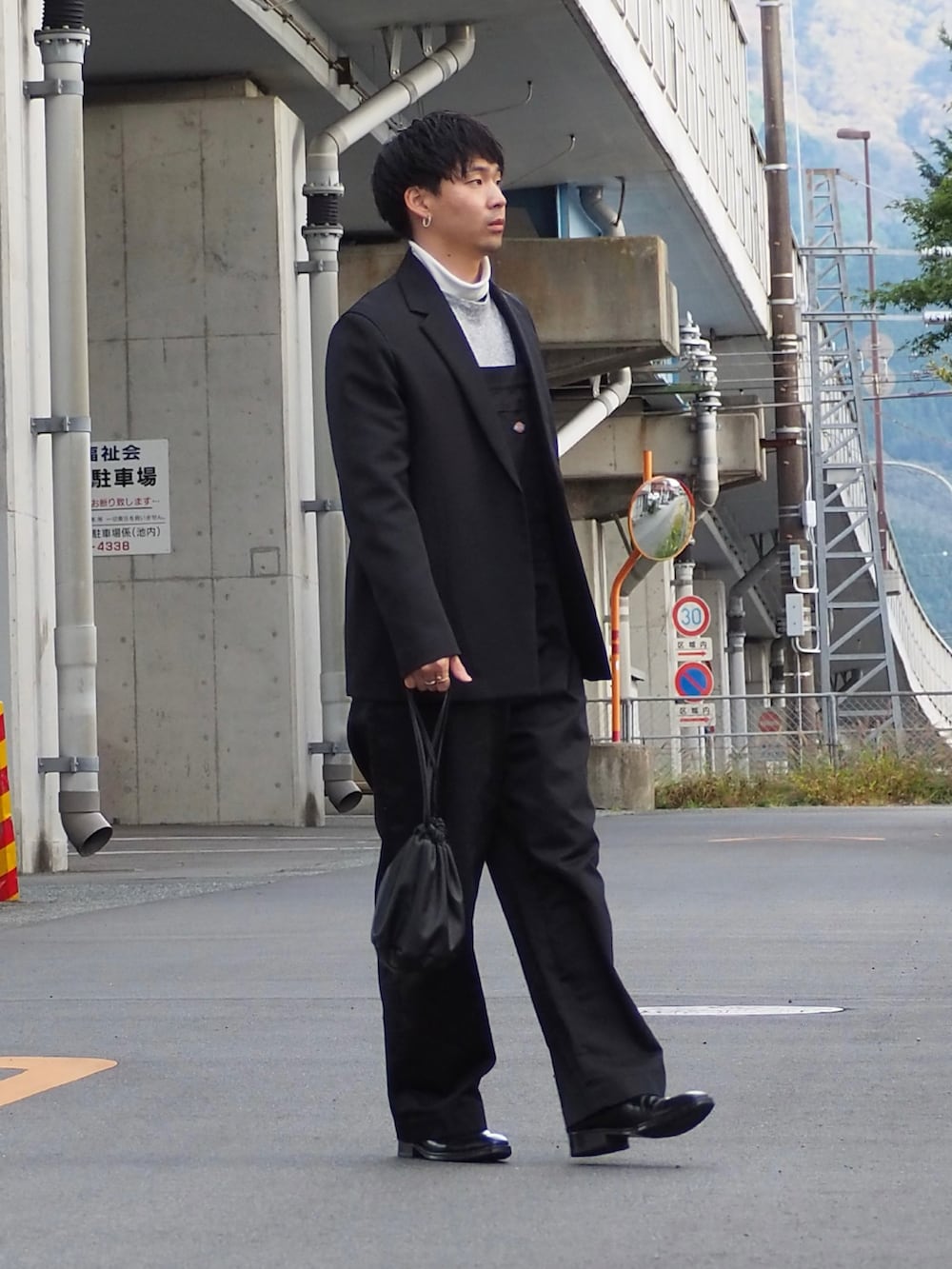 グレー系のニット/セーター、ブラック系のテーラードジャケット、ブラック系のショルダーバッグを着用したメンズの冬コーディネートの2枚目の写真