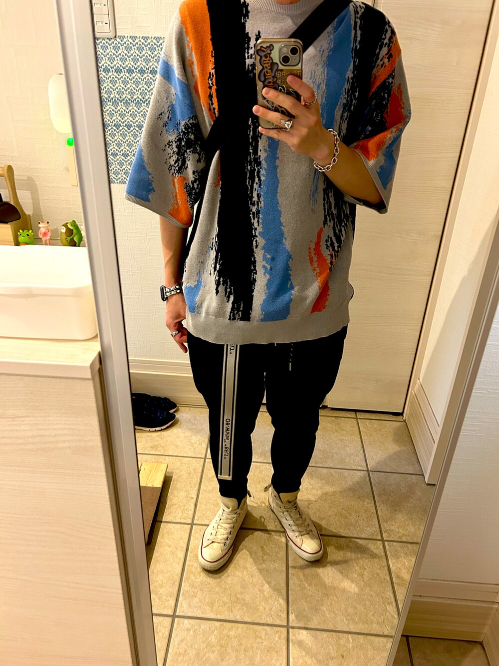 グレー系のニット/セーター、ブラック系のその他パンツ、ホワイト系のスニーカーを着用したメンズの春コーディネートの2枚目の写真