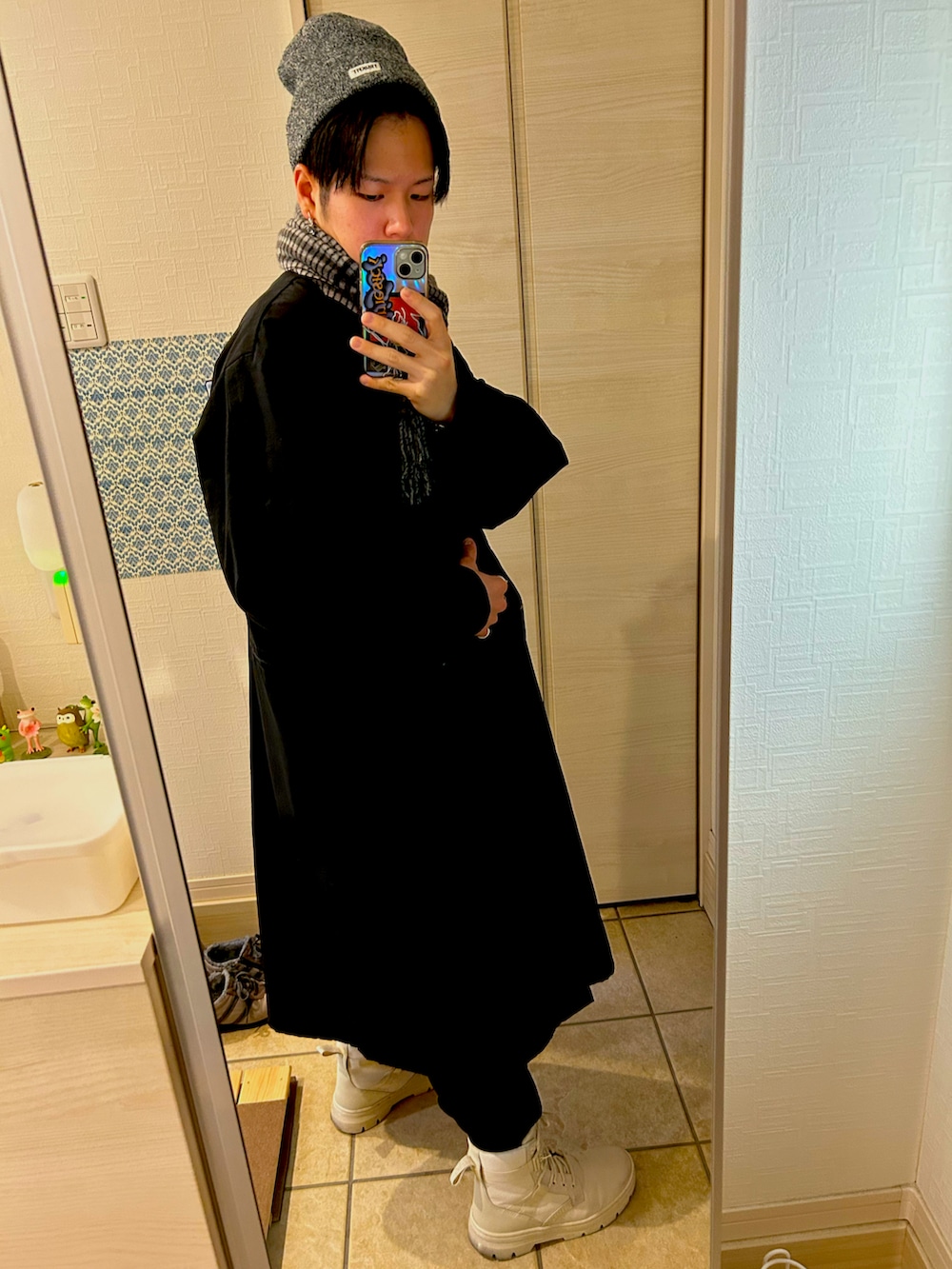 ブラック系のモッズコート、ホワイト系のブーツ、グレー系のニットキャップ/ビーニーを着用したメンズの春コーディネートの2枚目の写真