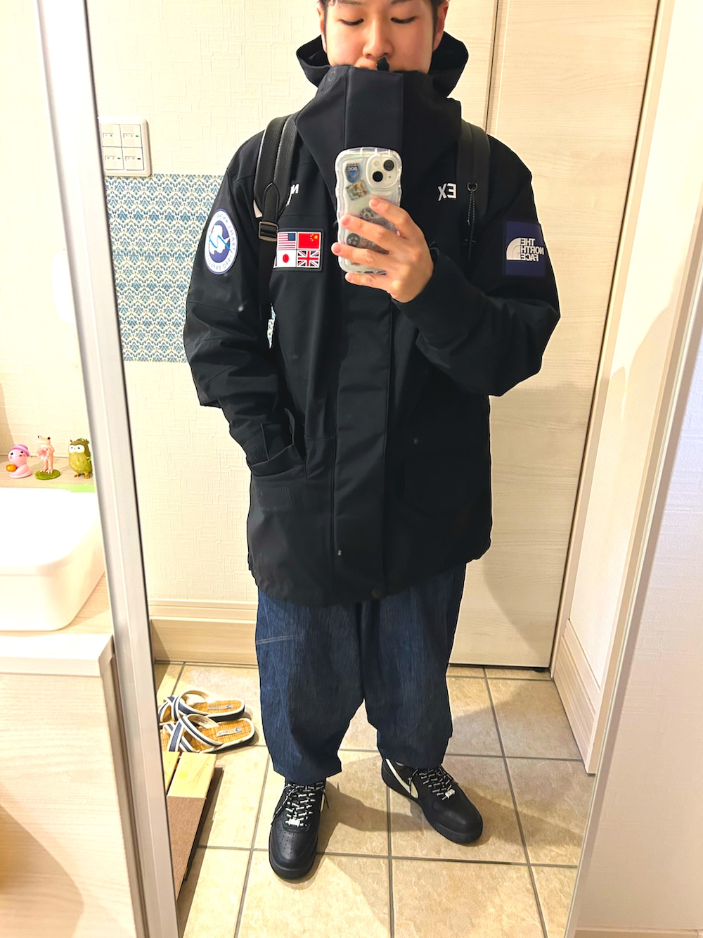 ブラック系のマウンテンパーカー、ブルー系のデニムパンツ、ブラック系のスニーカーを着用したメンズの冬コーディネートの2枚目の写真