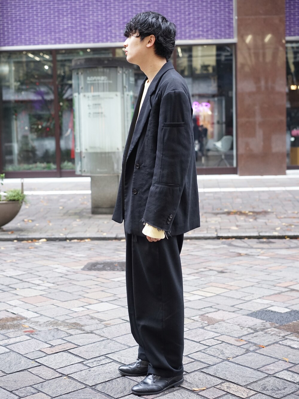 ブラック系のテーラードジャケット、ベージュ系のニット/セーター、ブラック系のスラックスを着用したメンズの秋コーディネートの5枚目の写真