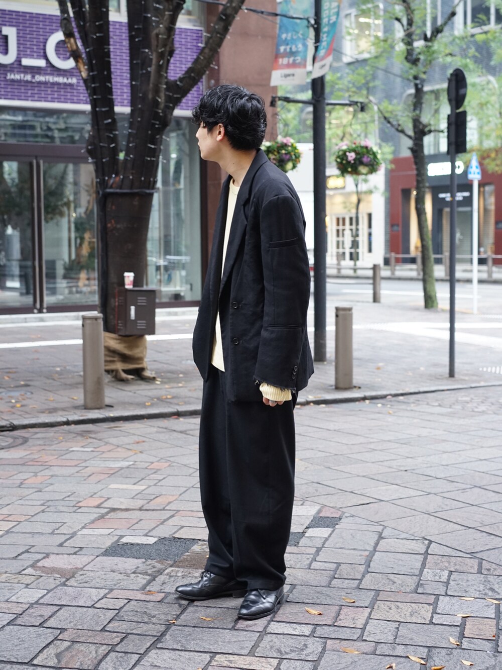 ブラック系のテーラードジャケット、ベージュ系のニット/セーター、ブラック系のスラックスを着用したメンズの秋コーディネートの4枚目の写真