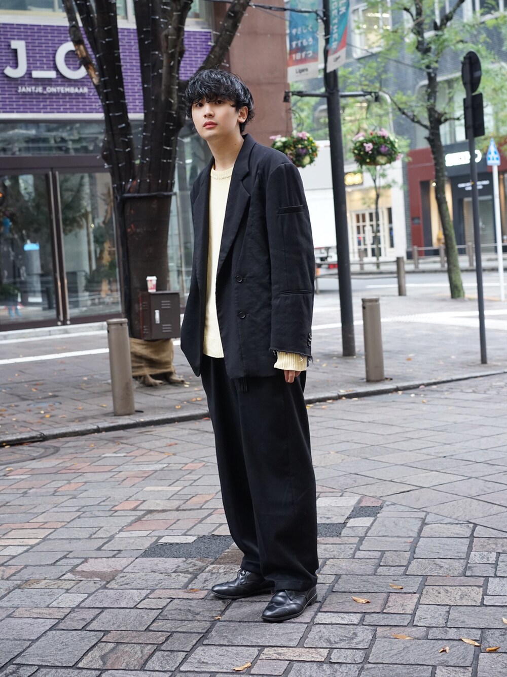 ブラック系のテーラードジャケット、ベージュ系のニット/セーター、ブラック系のスラックスを着用したメンズの秋コーディネートの3枚目の写真