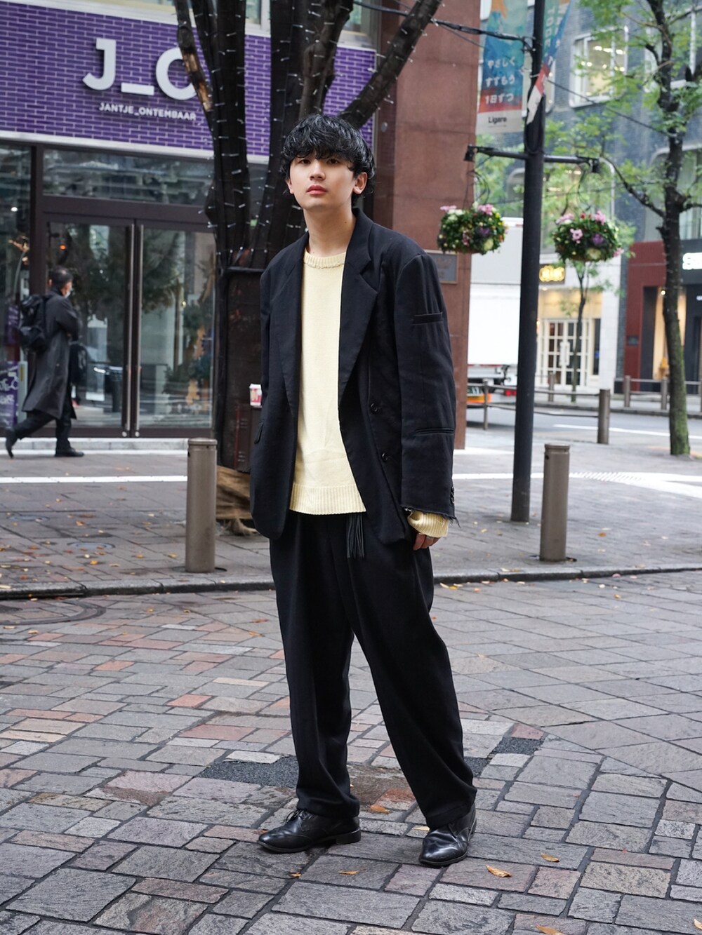 ブラック系のテーラードジャケット、ベージュ系のニット/セーター、ブラック系のスラックスを着用したメンズの秋コーディネートの2枚目の写真