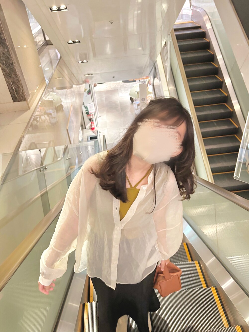 ブラック系のスカート、イエロー系のタンクトップ、ブラウン系のショルダーバッグを着用したレディースの春コーディネートの2枚目の写真