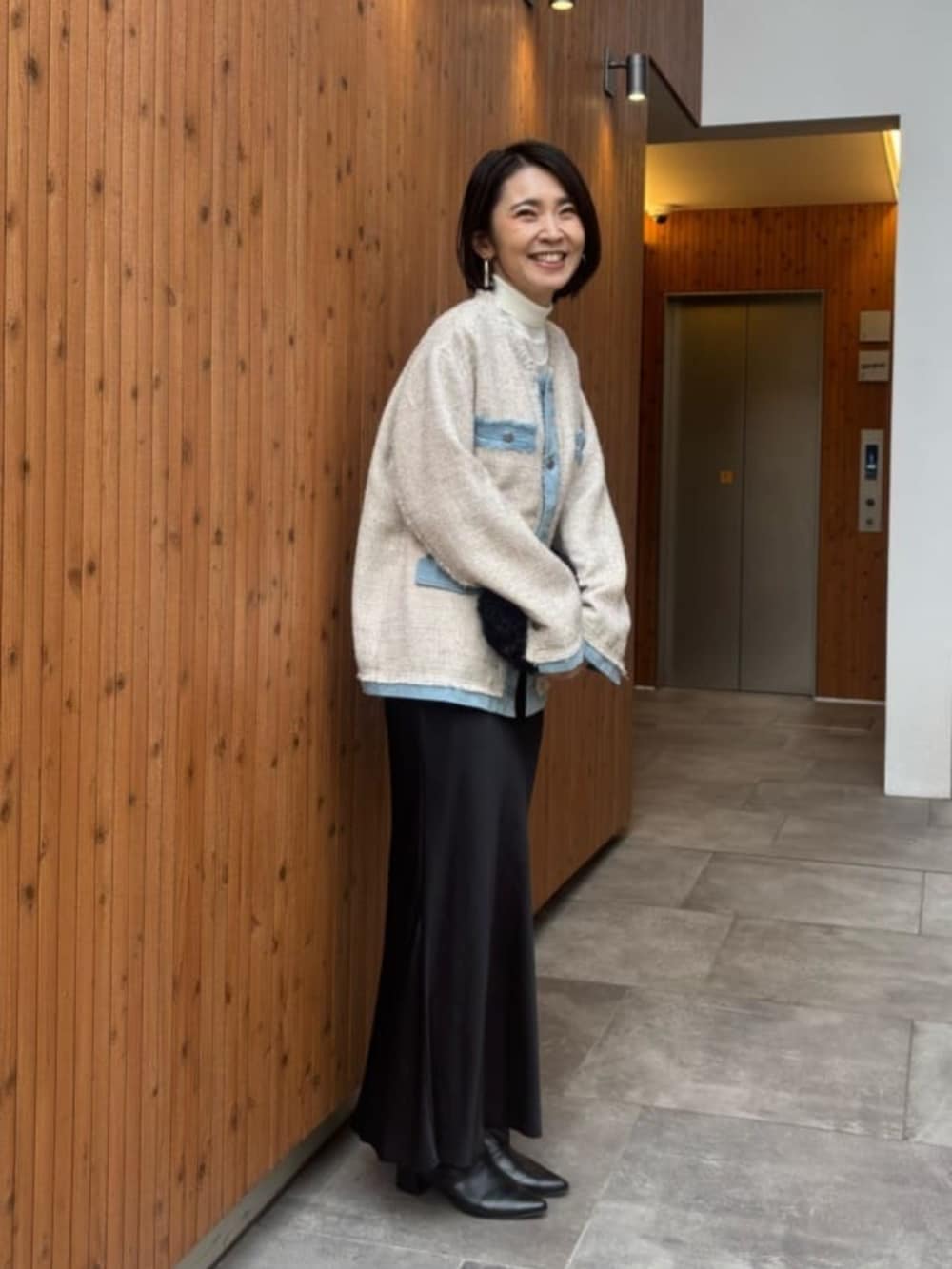 ブラック系のスカート、ホワイト系のノーカラージャケットを着用したレディースの冬コーディネートの5枚目の写真